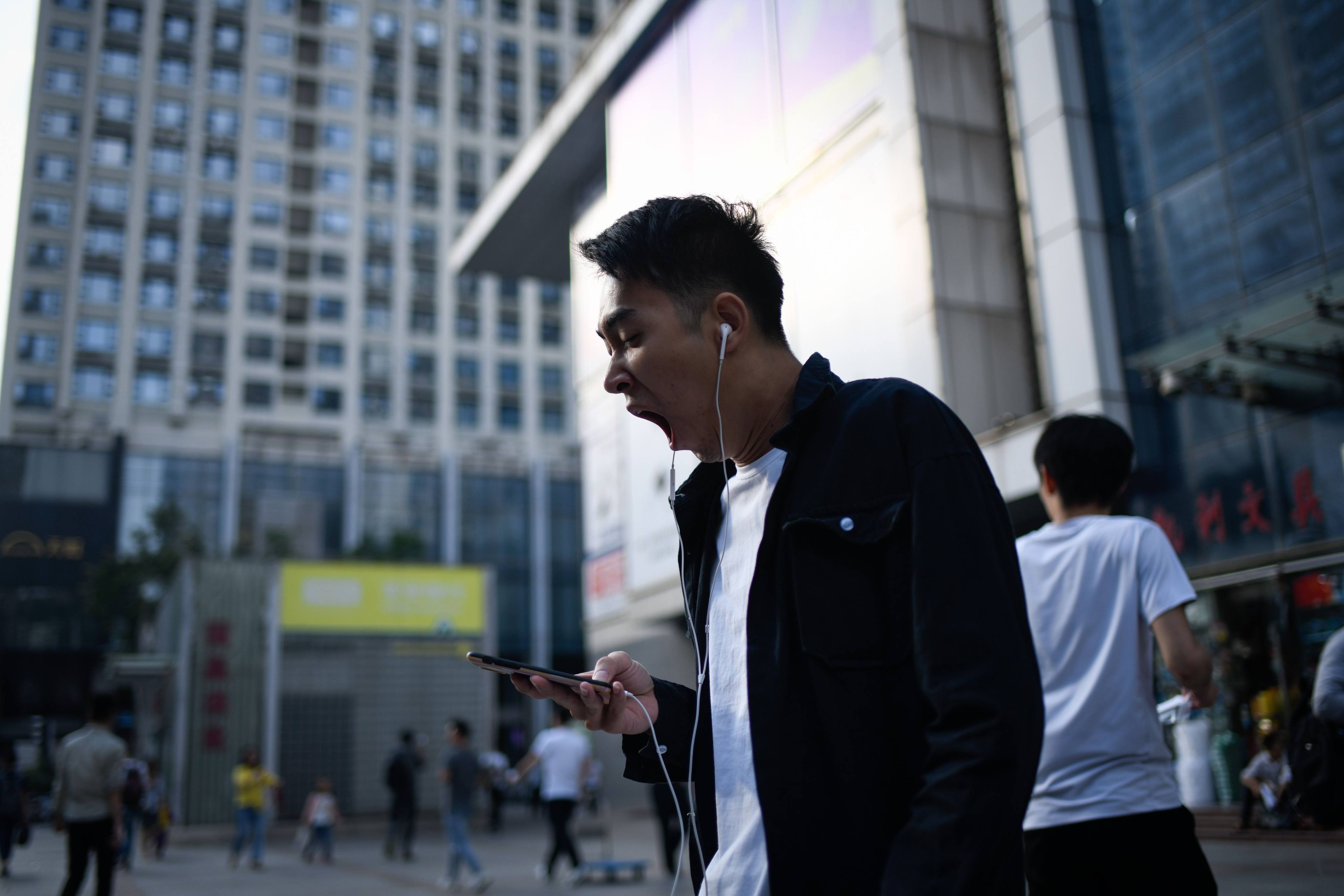 A man yawns as he walks down a street in Shenzhen in 2018. Young tech employees in China have taken to the internet to complain about long working hours. Photo: AFP