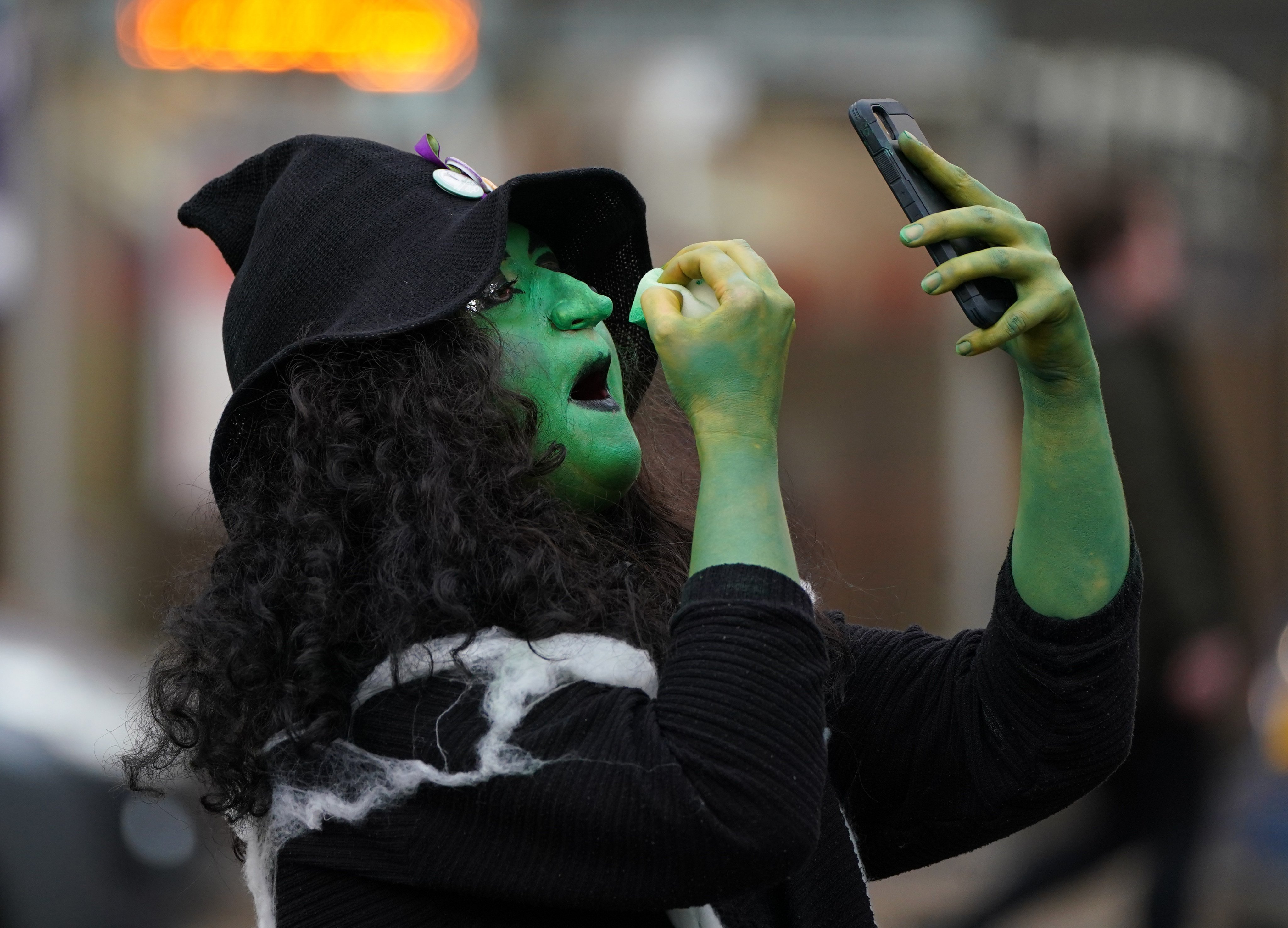 A woman from the campaign group Women Won’t Wheesht dressed as a witch touches up her make-up in George Square, Glasgow, at the start of the COP26 climate summit on October 31. Photo: dpa