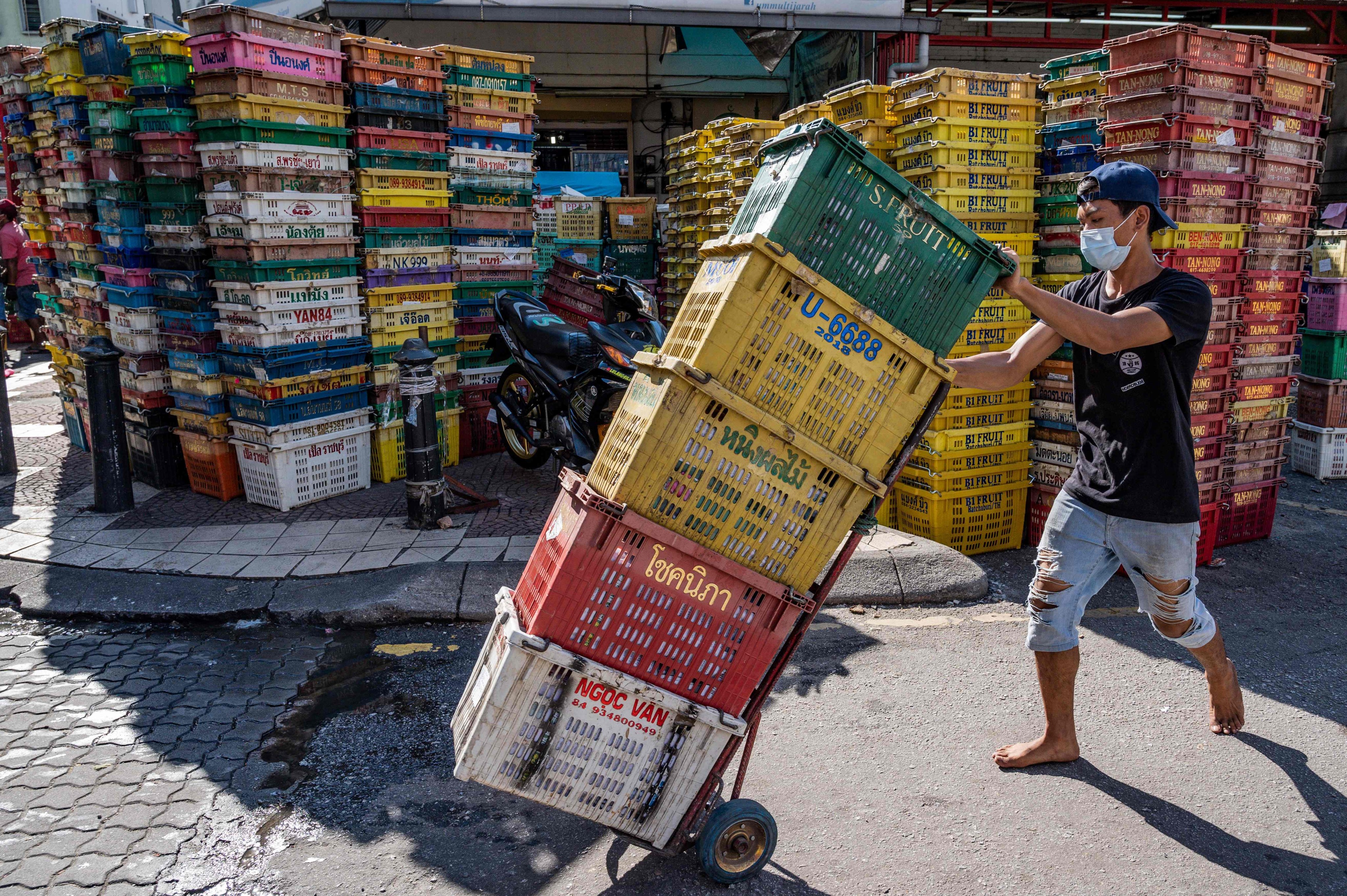 A worker pushes empty crates at a fruit market in Kuala Lumpur. Photo: AFP 
