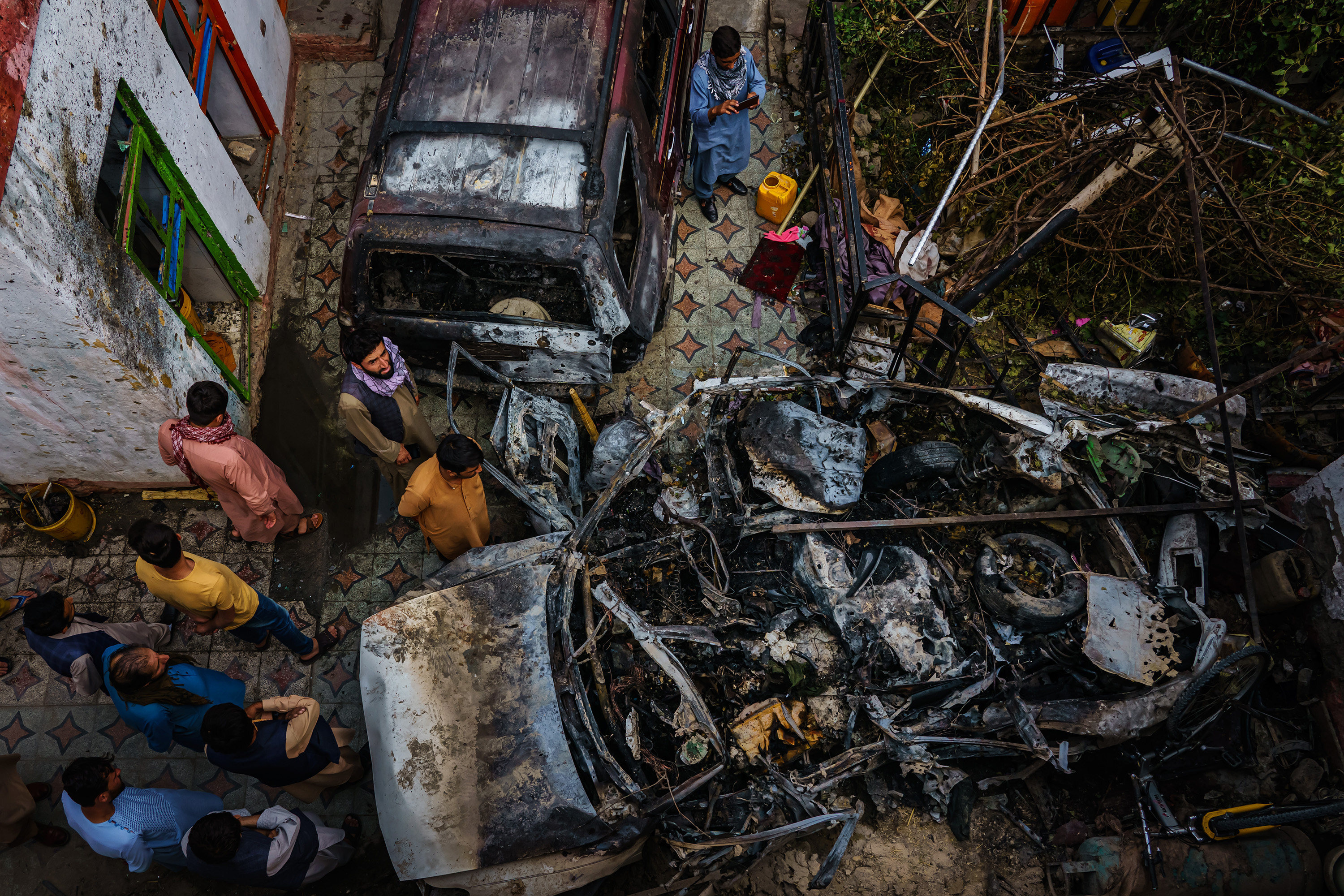 Relatives and neighbours of the Ahmadi family gather around the wreckage of a vehicle that the family says was hit by a US drone strike in Kabul, Afghanistan, on August 30. Photo: TNS