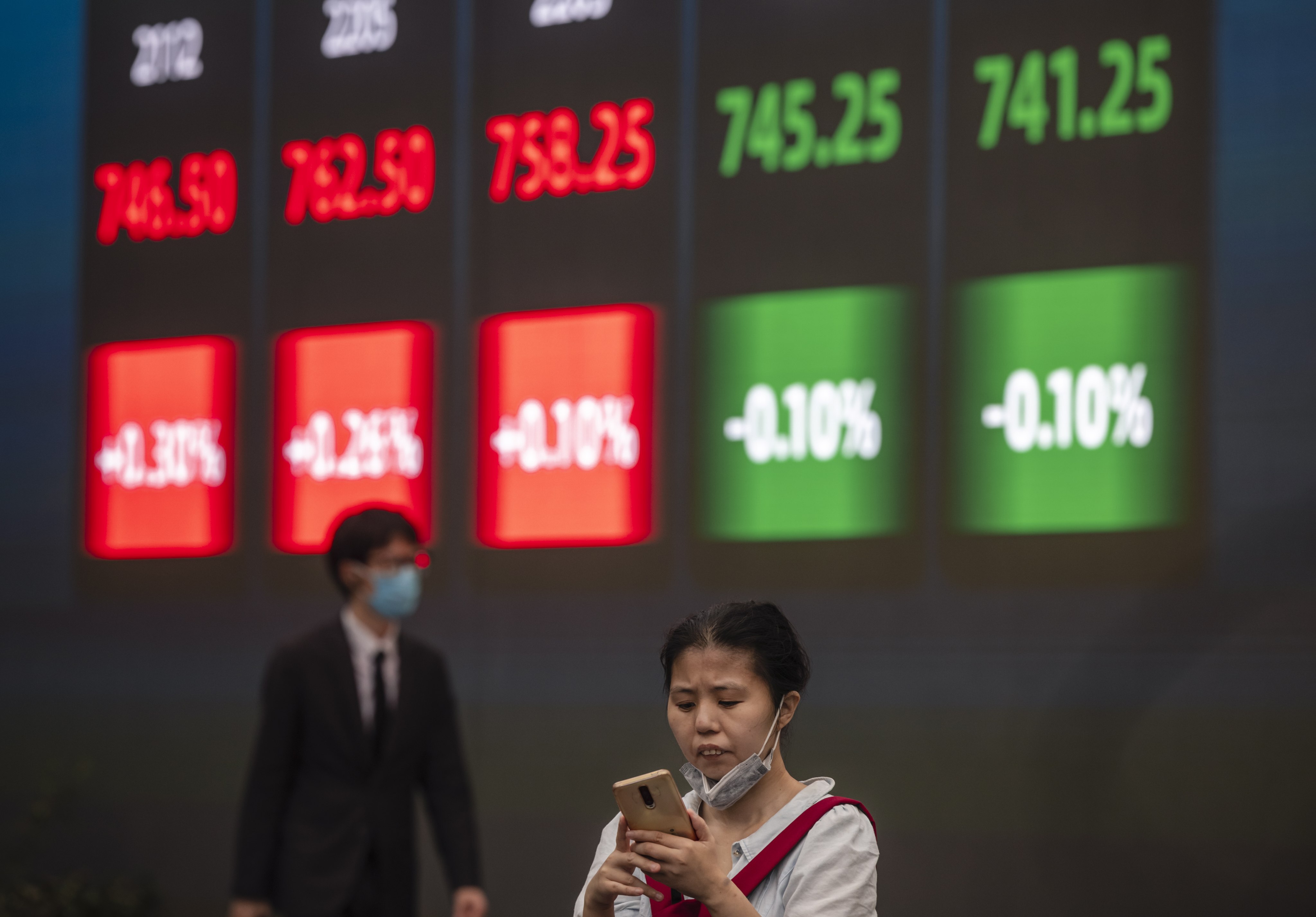 A woman stands in front of a screen showing stock exchange and economic data in Shanghai, on October 7. Photo: EPA-EFE
