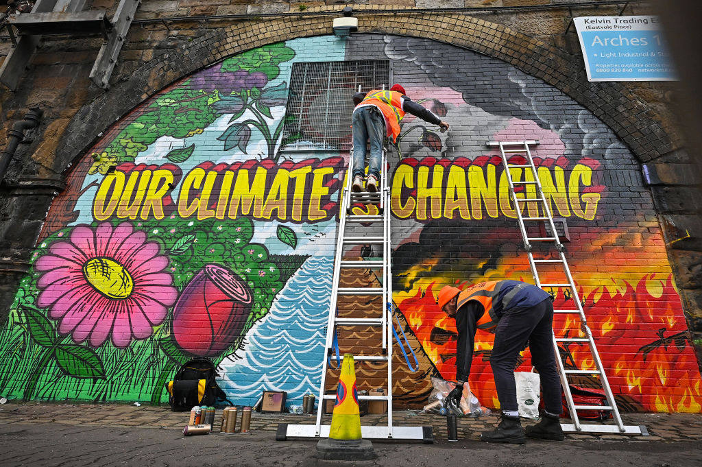 Artists paint a climate change mural on a wall in Glasgow, Scotland. Traditional marketing needs to give way to advertising that promotes the message that making greener choices is possible, insiders say. Photo: Getty Images