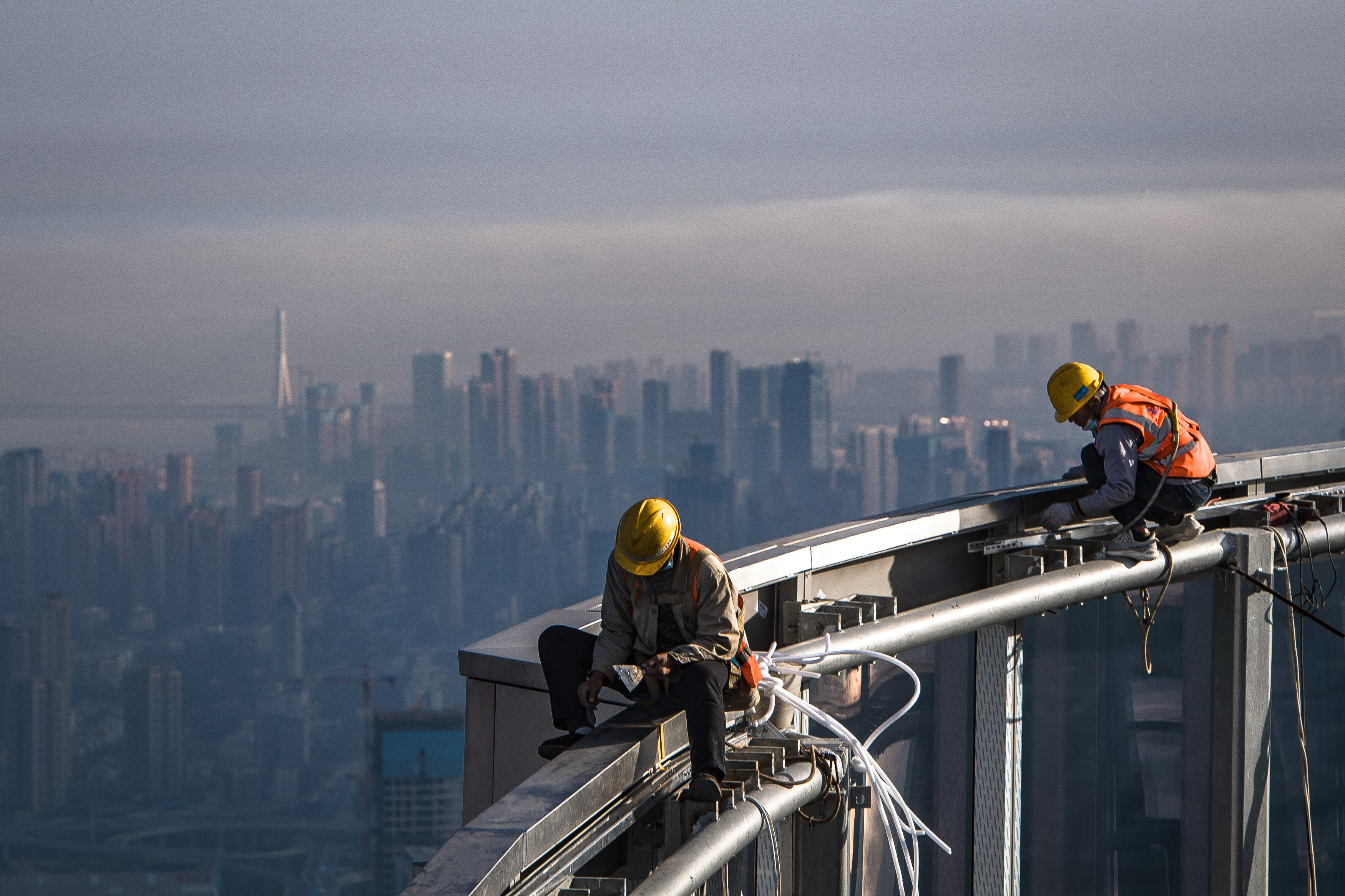 Workers perch on a skyscraper being built in Wuhan, China, on November 15. China’s drive to control excessive leverage in the property sector has seen some developers struggle to avoid defaulting on their debt. Photo: Xinhua