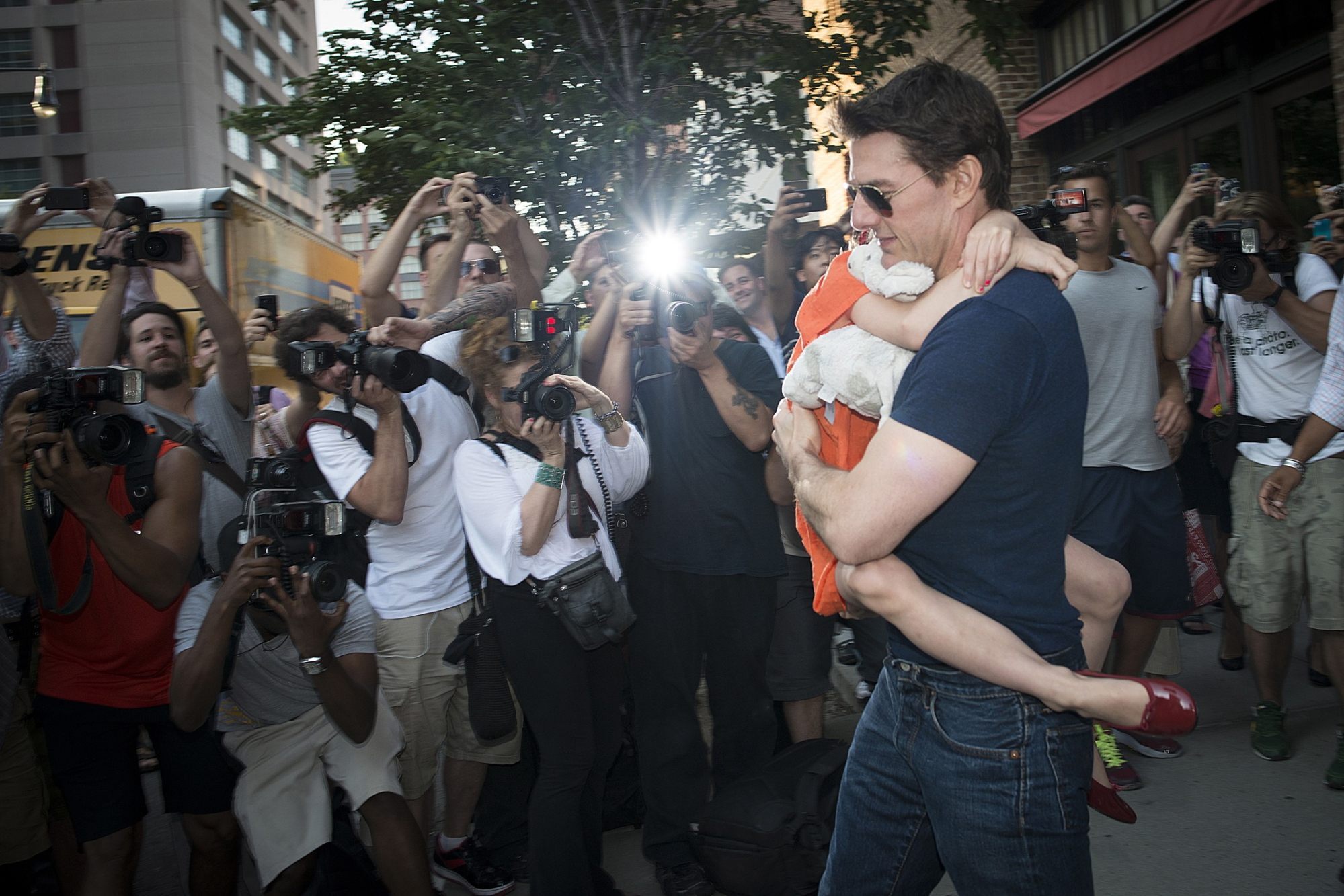 Actor Tom Cruise carries his daughter Suri past photographers as they make their way from a hotel in New York, in July 2012. Photo: Reuters