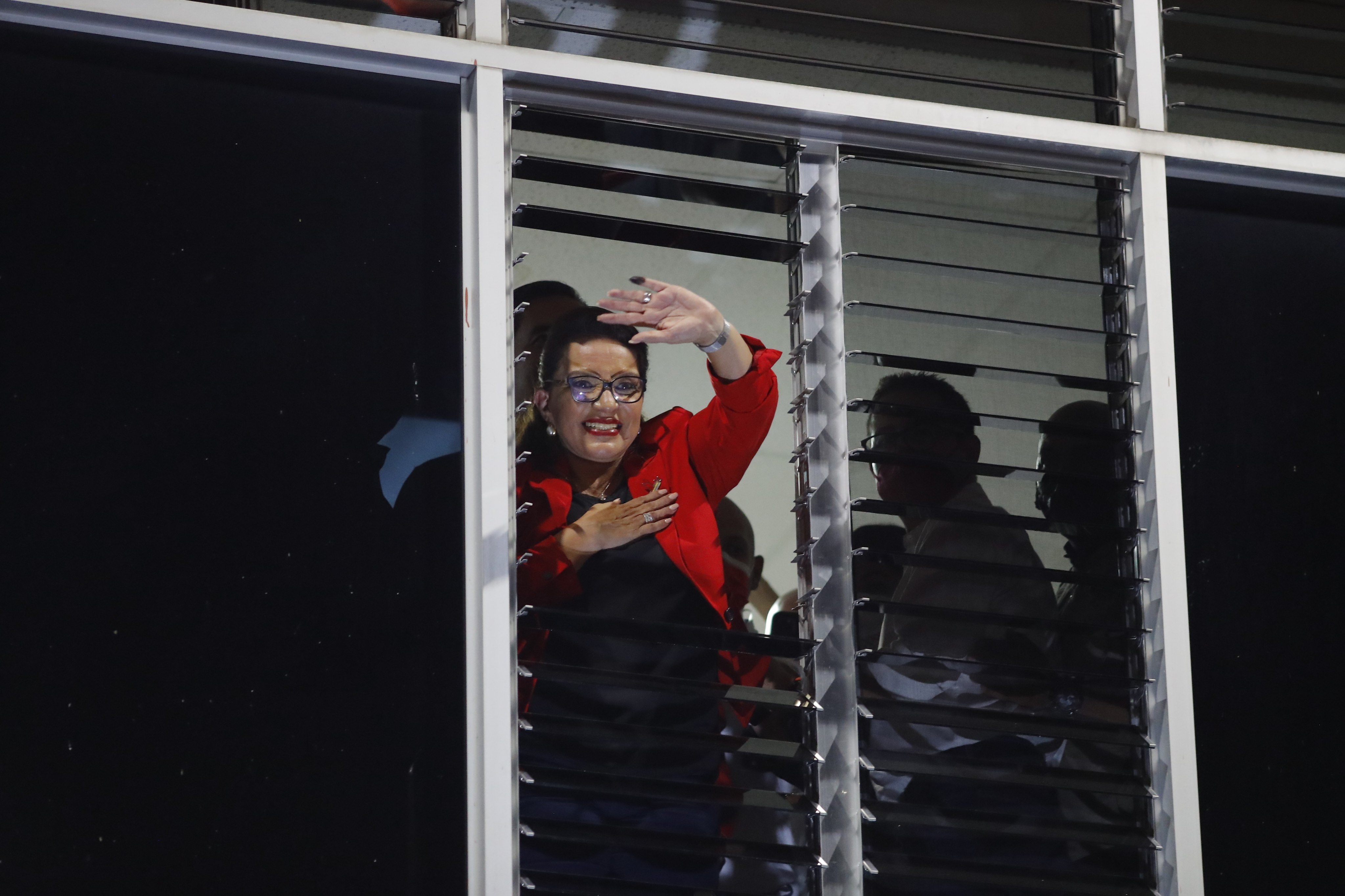 Honduras presidential candidate Xiomara Castro greets supporters from a window in Tegucigaloa after hearing the partial results of the elections. Photo: EPA
