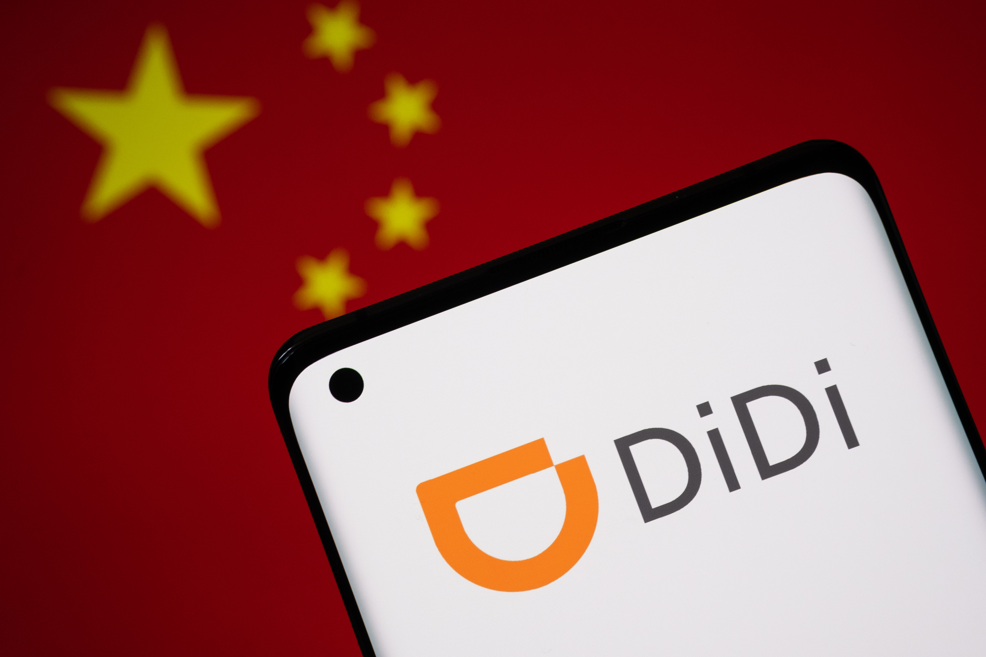 Didi’s logo seen on a smartphone with a Chinese flag in the background. Photo: Shutterstock Images