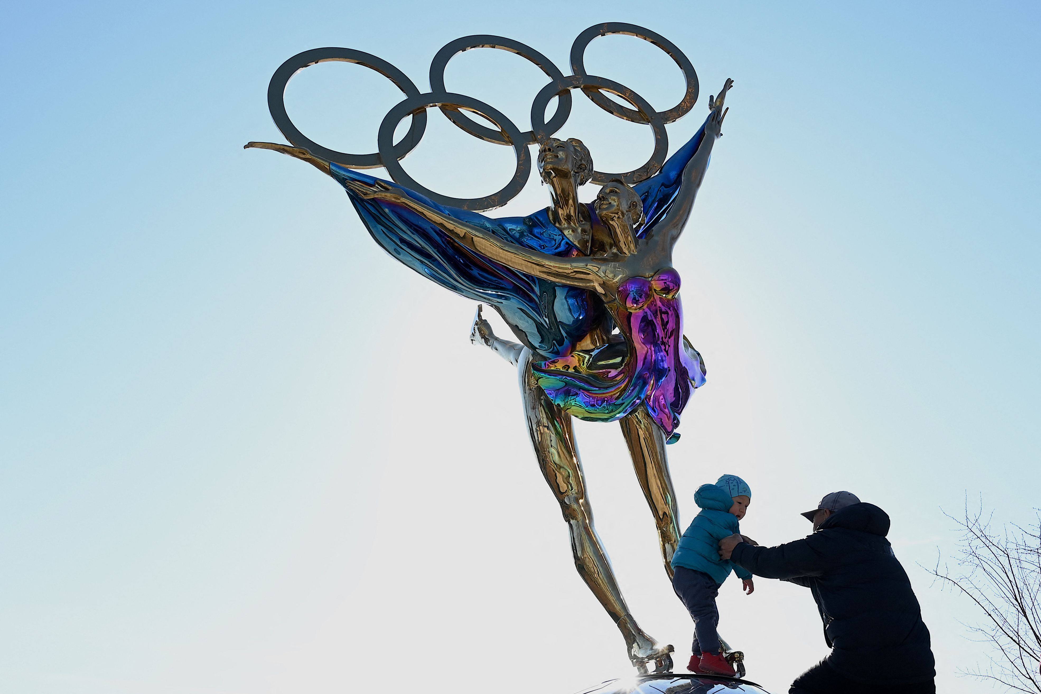 A child stands on a statue with the Olympic Rings titled “Dating With the Winter Olympics” by Huang Jian, near the headquarters of the Beijing Organizing Committee in Shougang Park. Photo by Noel Celis / AFP