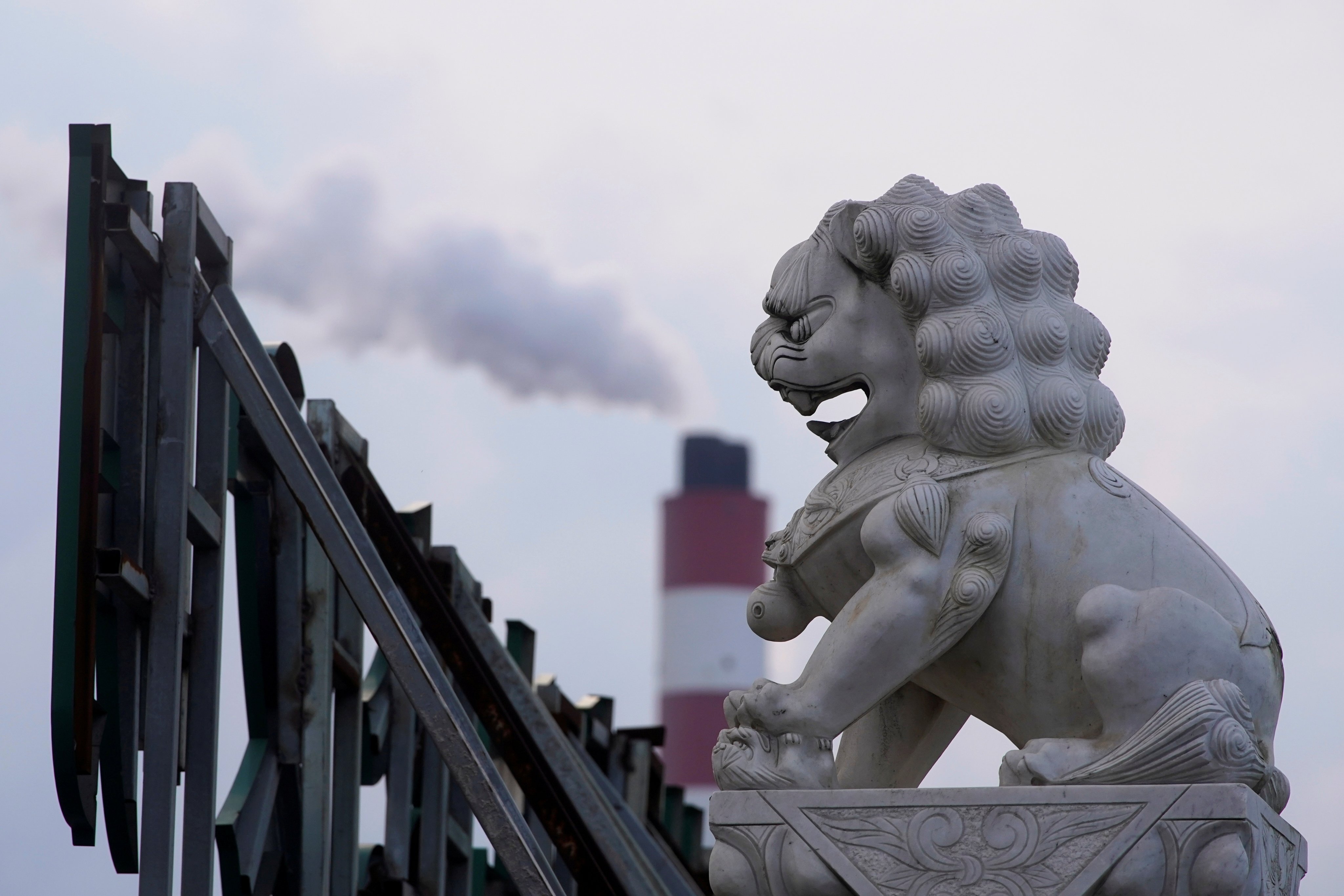 The chimney of a coal-fired power plant stands behind a lion statue in Shanghai on October 21, 2021. Photo: Reuters
