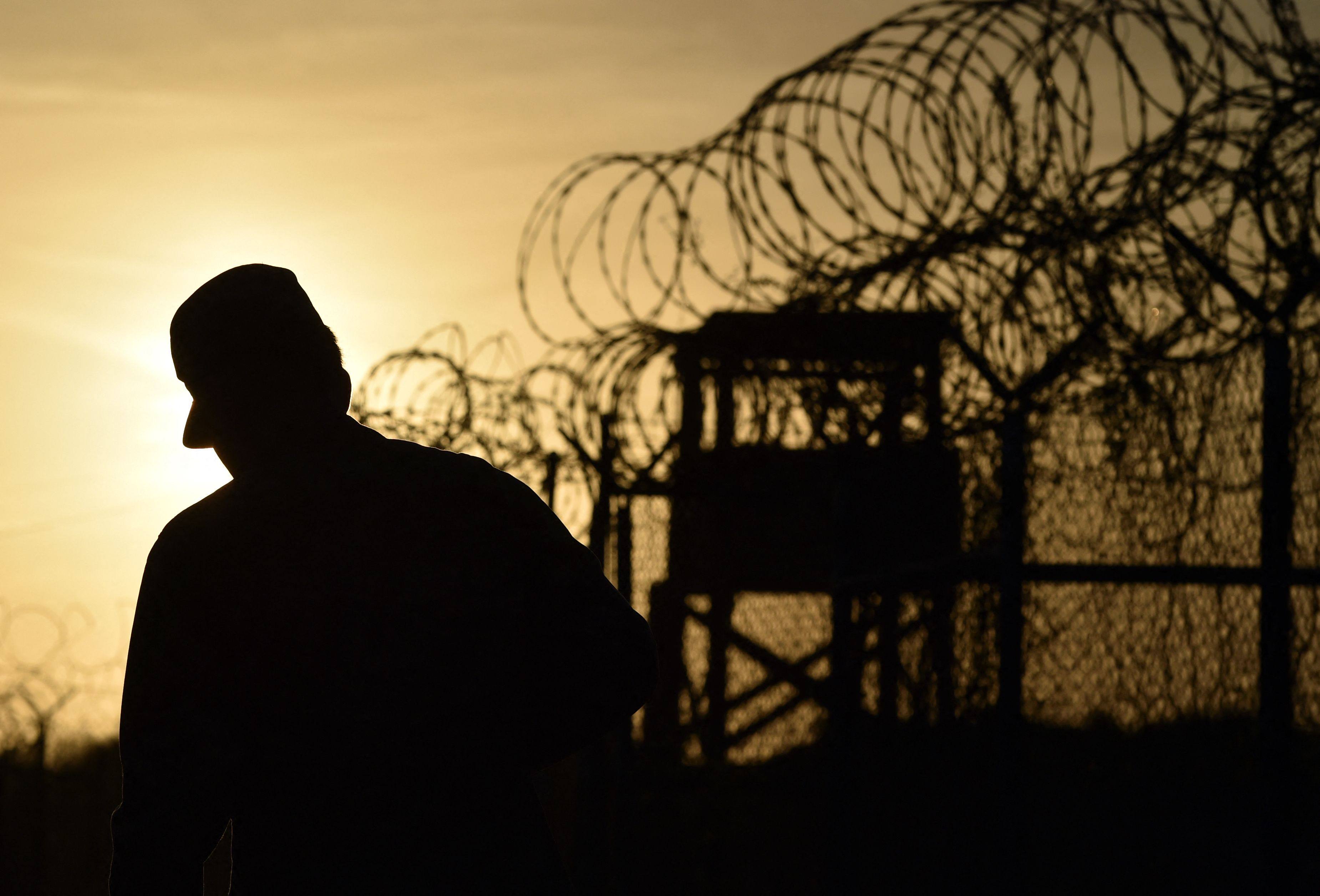A US soldier walks next to the razor wire-topped fence at Guantanamo Bay, Cuba. Photo: AFP