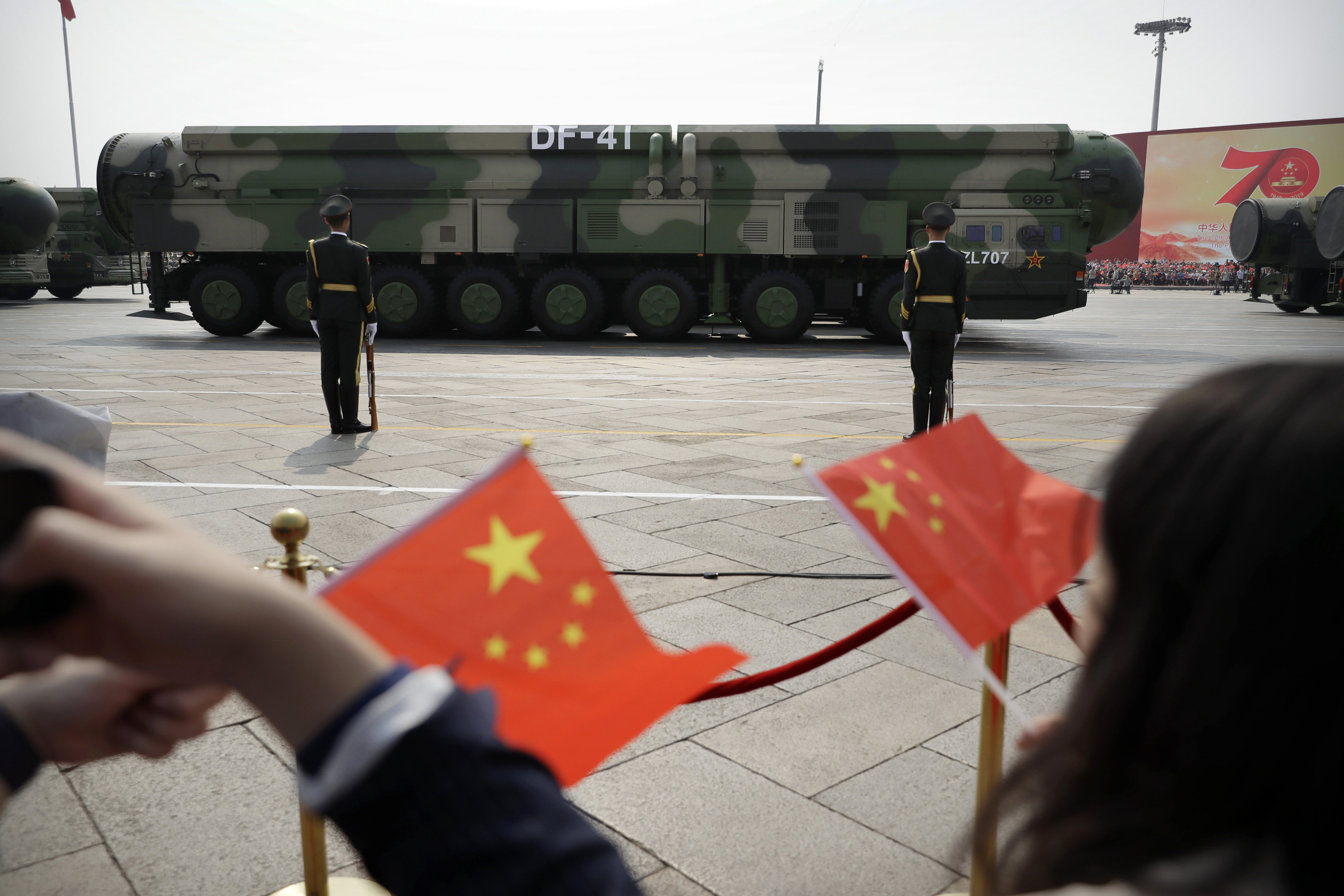 Spectators wave Chinese flags as military vehicles carrying DF-41 ballistic missiles roll past during a parade on October 1, 2019. China is expanding its nuclear force much faster than US officials predicted. Photo: AP
