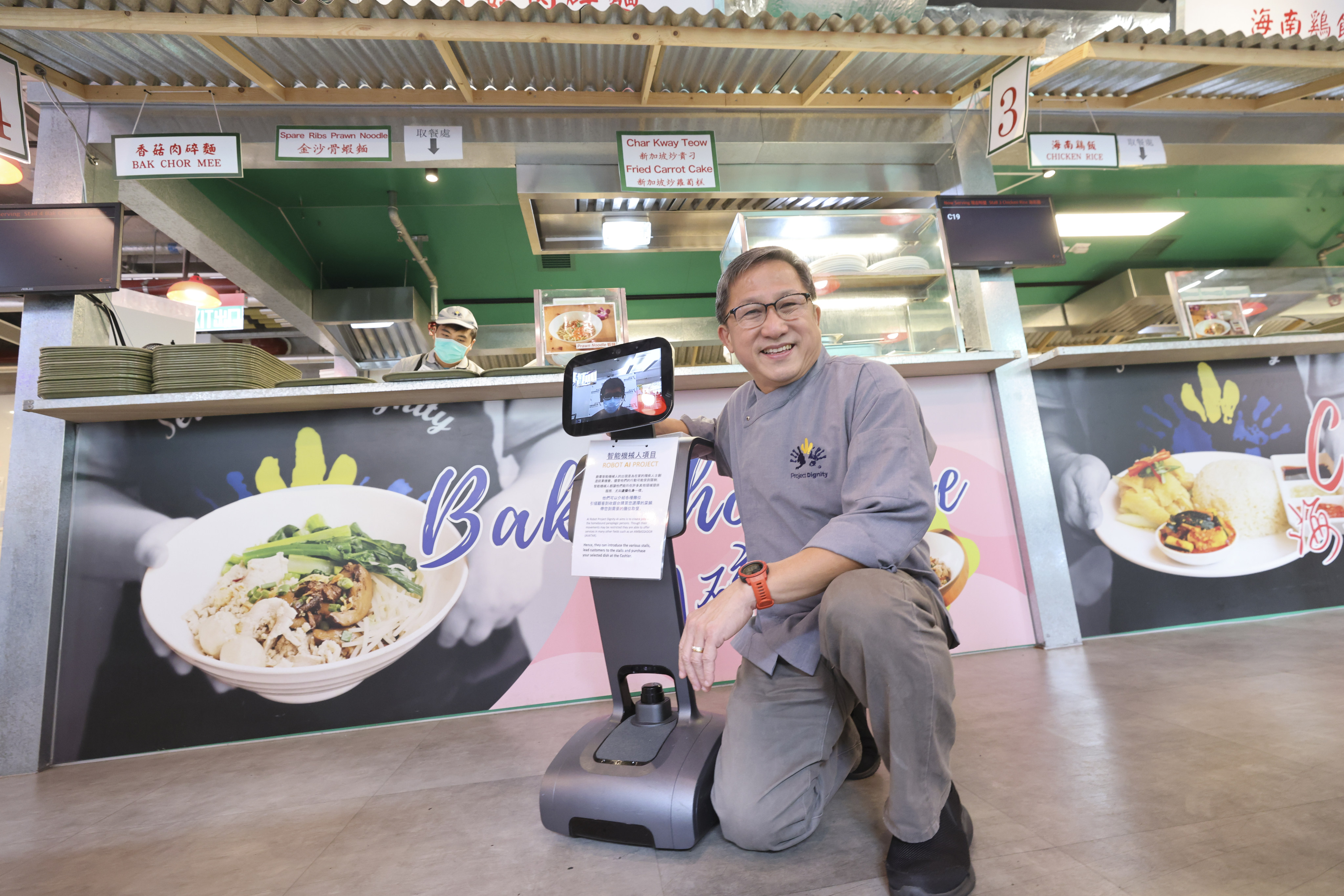 Dignity Kitchen founder Koh Seng Choon (right) with paraplegic Eddie Lau (on the tablet screen) who operates Temi, the robot, remotely. Photo: May Tse