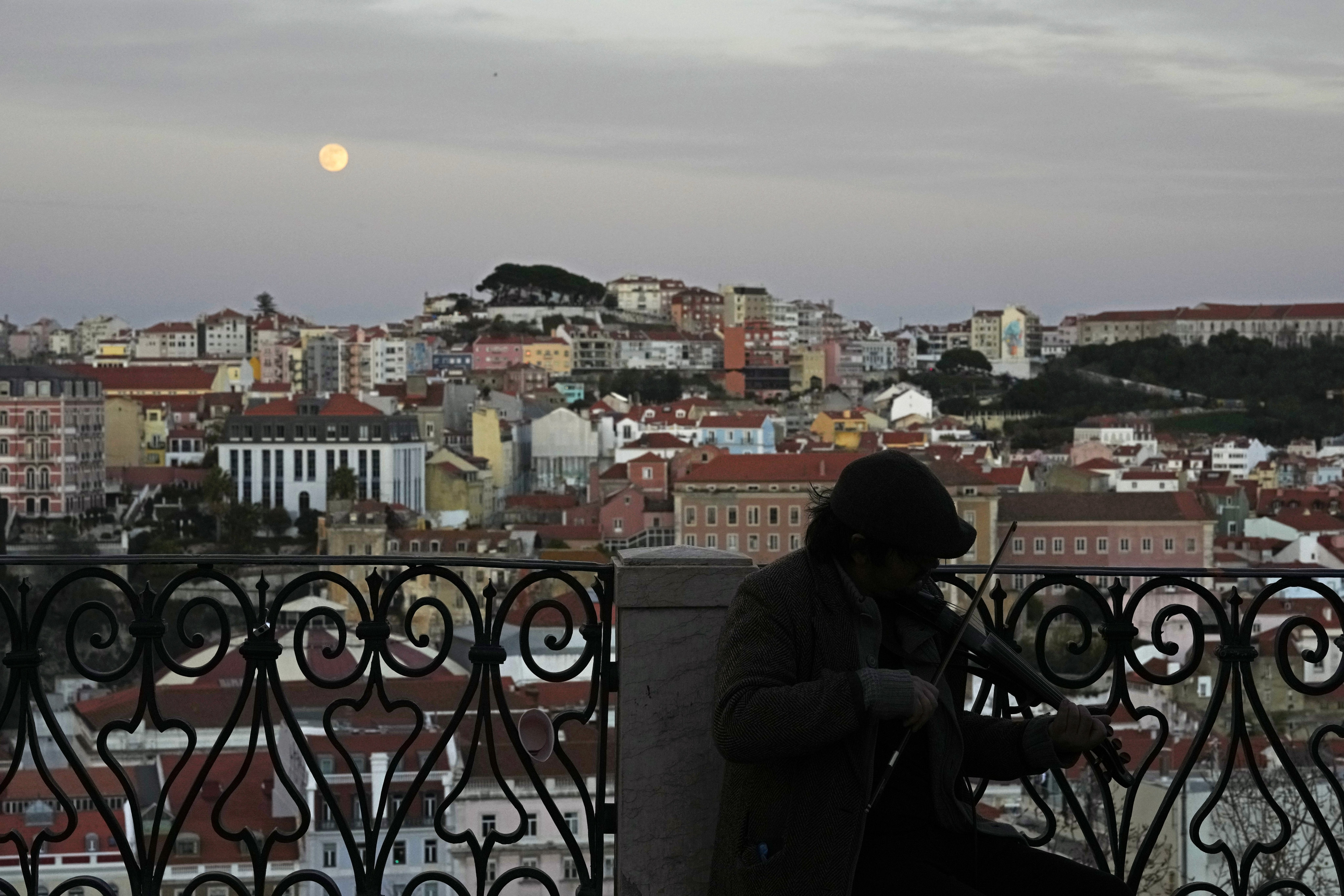A young man plays the violin as night falls in Lisbon, the Portuguese capital. Photo: AP