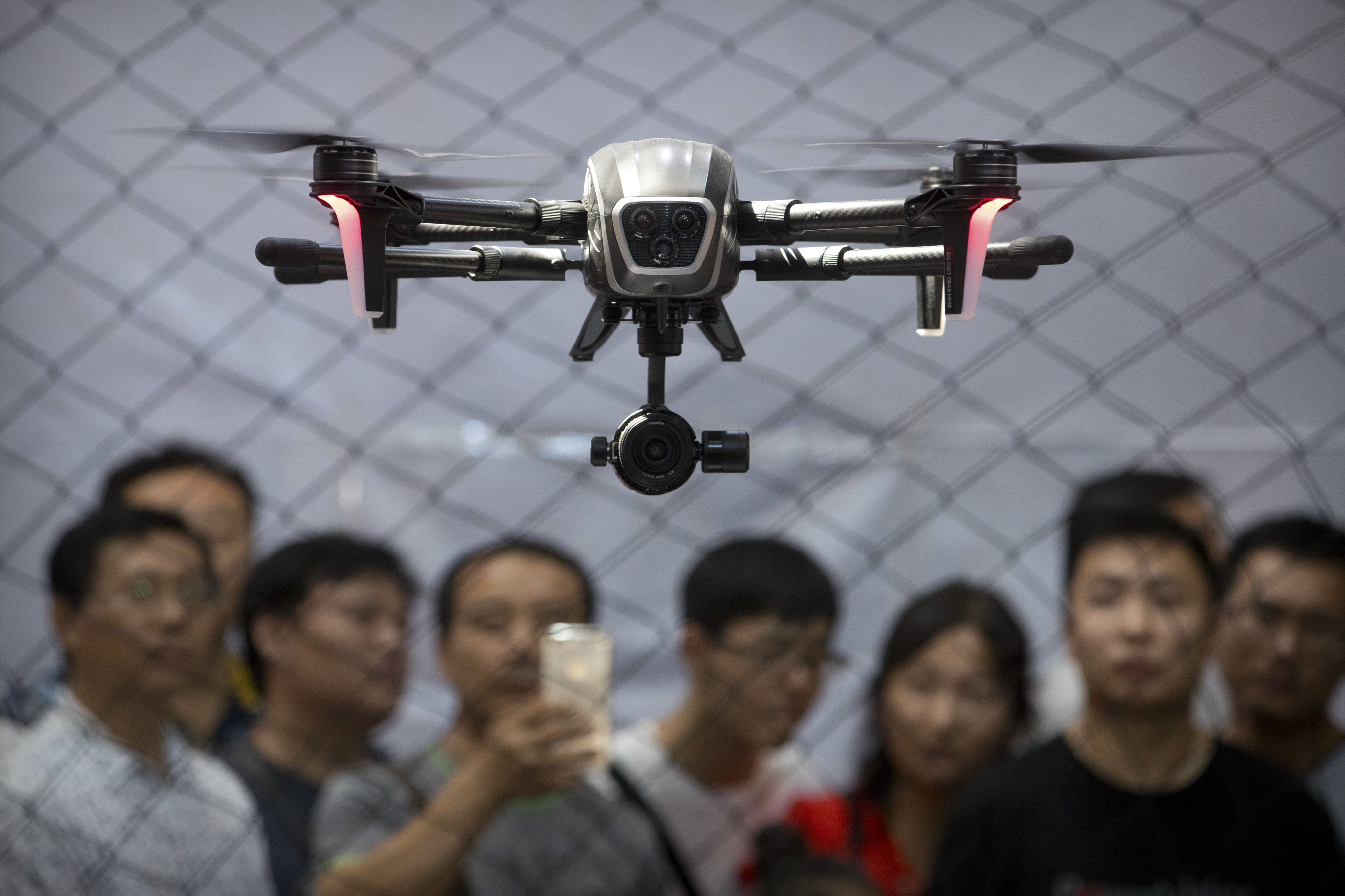 Visitors watch as a drone made by PowerVision hovers during a demonstration at the World Robot Conference in Beijing, Thursday, Aug. 24, 2017. The annual conference is a showcase of China&#39;s burgeoning robot industry ranging from companion robots to those deployed on manufacturing assembly line and entertainment. (AP Photo/Mark Schiefelbein)
