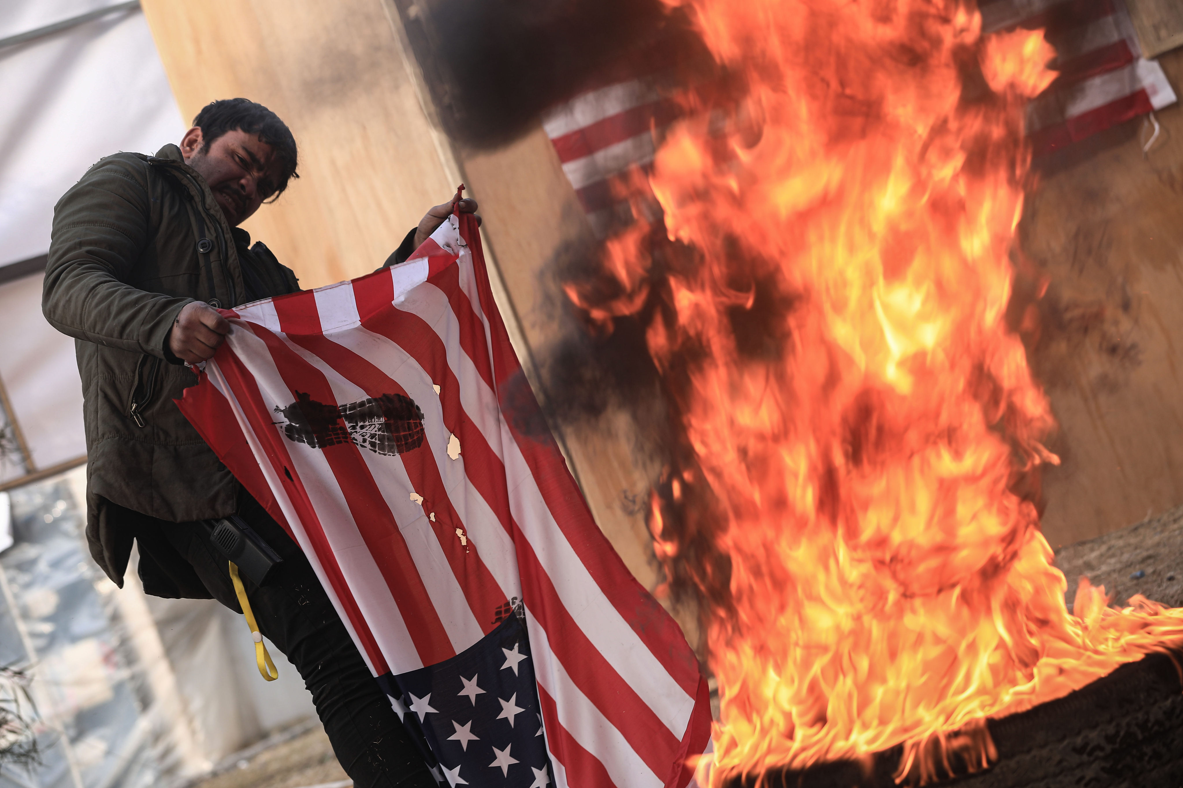 A man burns the US flag during a rally in front of the gate of Baghdad’s Green Zone on December 31, to mark the withdrawal of American combat troops from Iraq. Photo: dpa