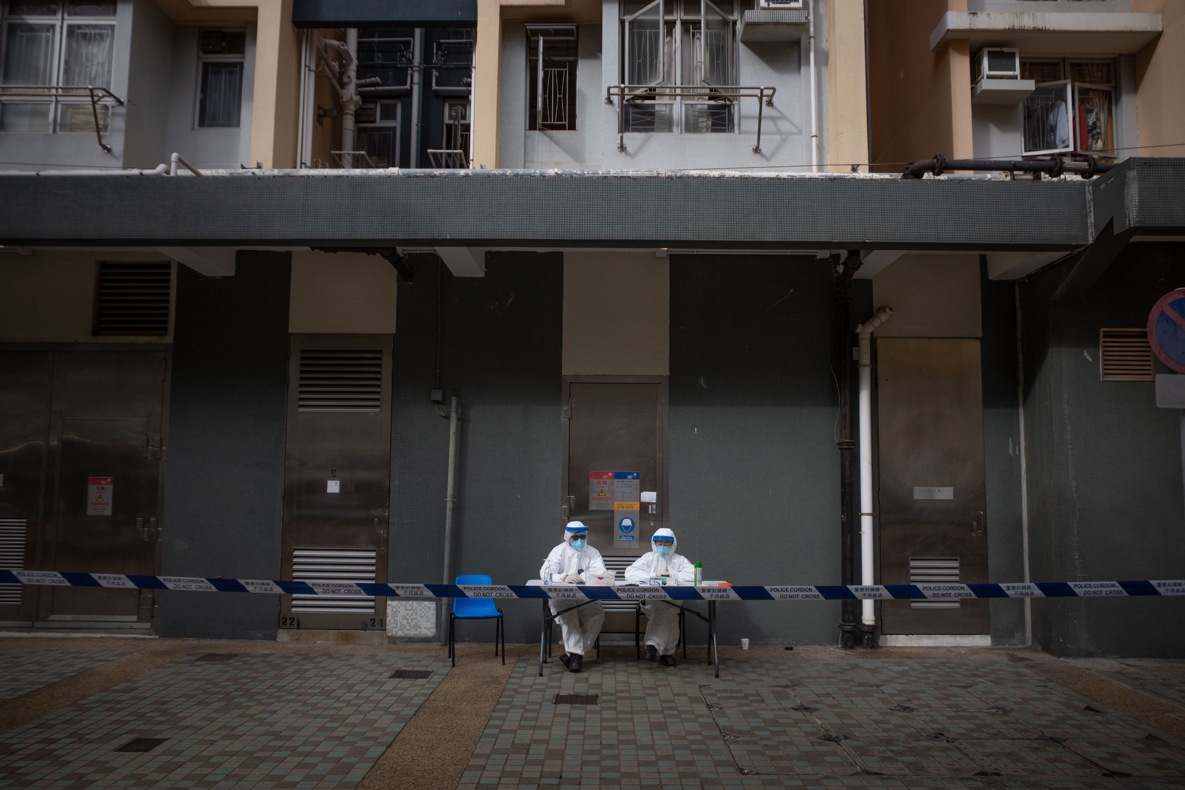 Health officials wearing personal protective equipment sit outside a residential building at the Kwai Chung Estate in Hong Kong, on January 23, after the government placed buildings at the public housing complex under lockdown. Photo: Bloomberg