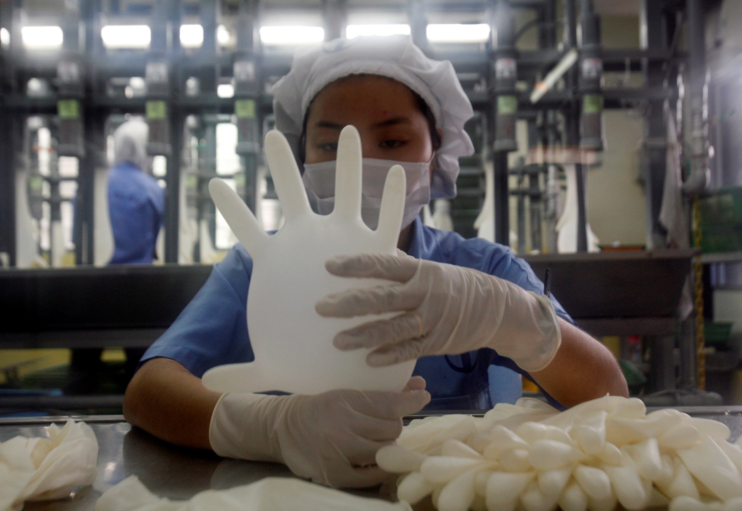 A worker carries out a test on a glove at a factory in Malaysia. Photo: Reuters