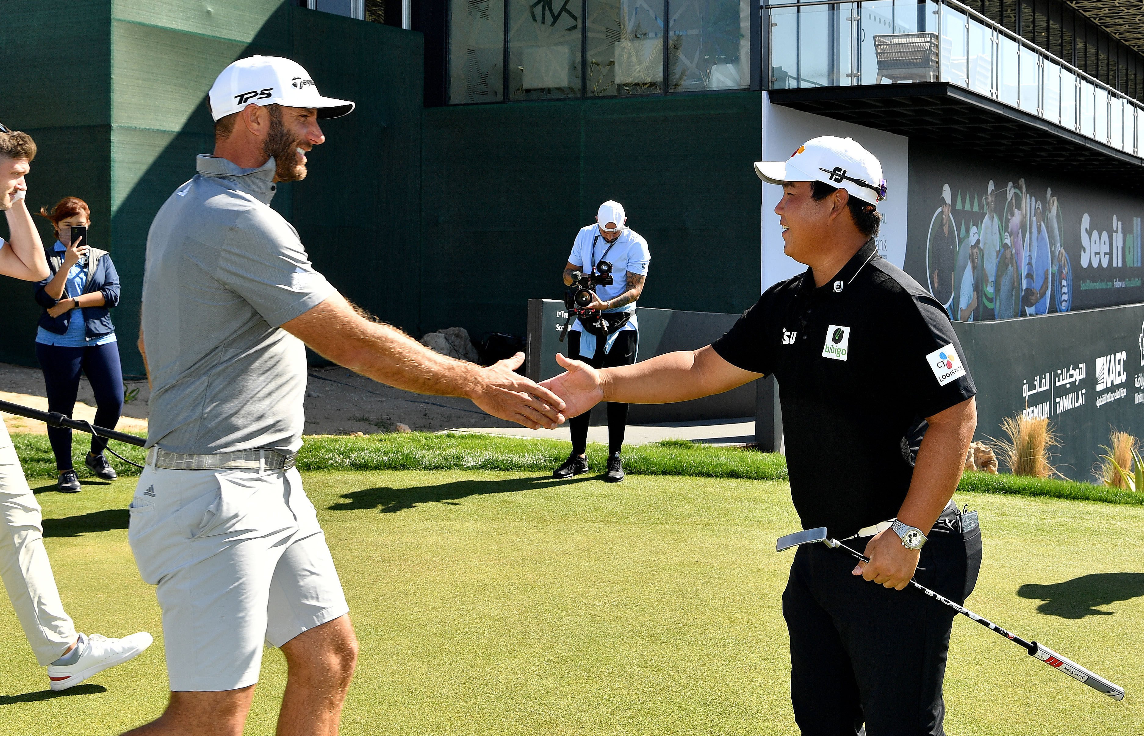 Dustin Johnson and Joohyung Kim meet on the putting green on Tuesday at the Royal Greens Golf and Country Club. Photo: Asian Tour.