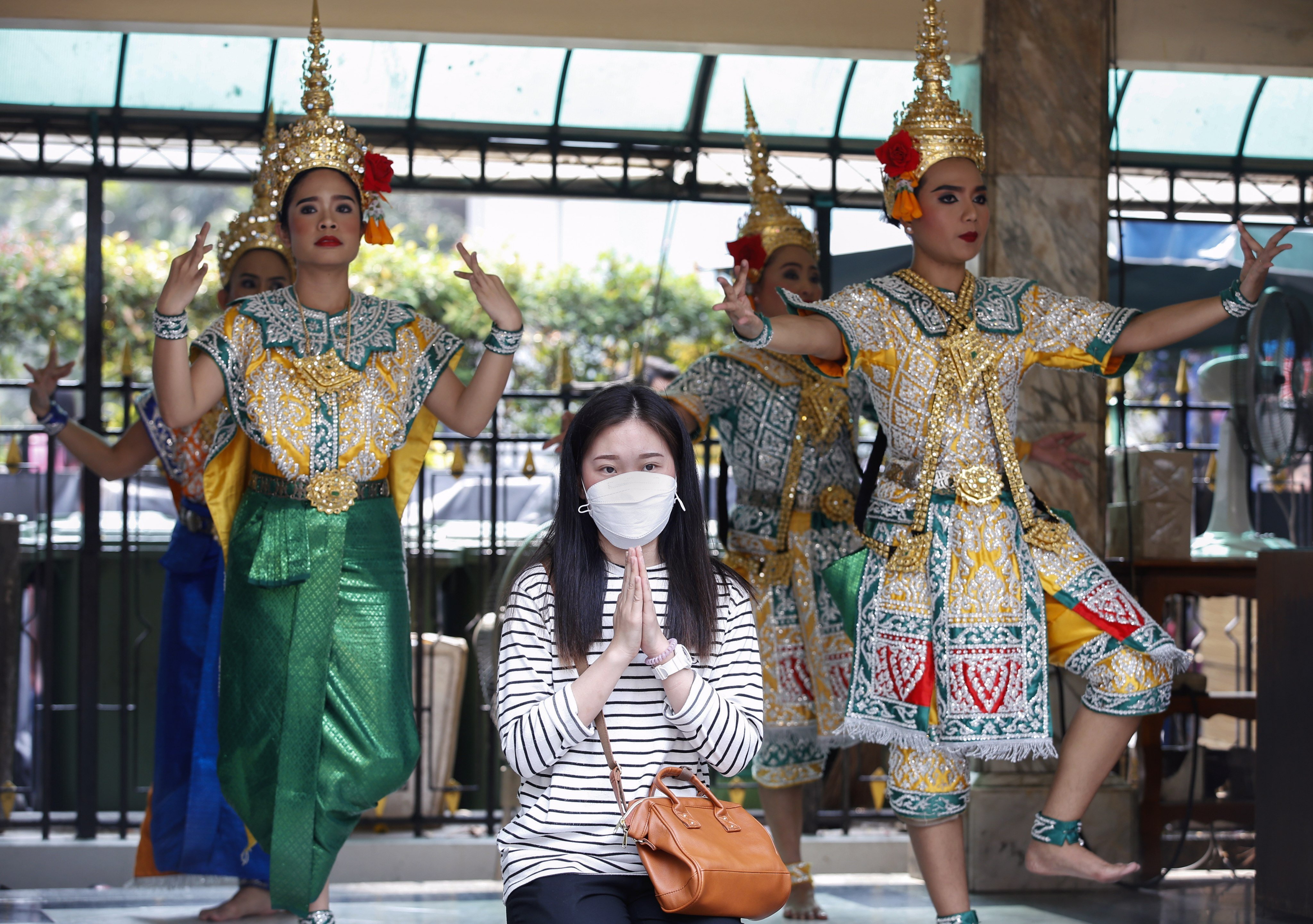 A woman prays as Thai dancers perform at the Erawan Shrine in Bangkok, Thailand,  a popular spot for Chinese tourists before the outbreak of the coronavirus. Photo: EPA