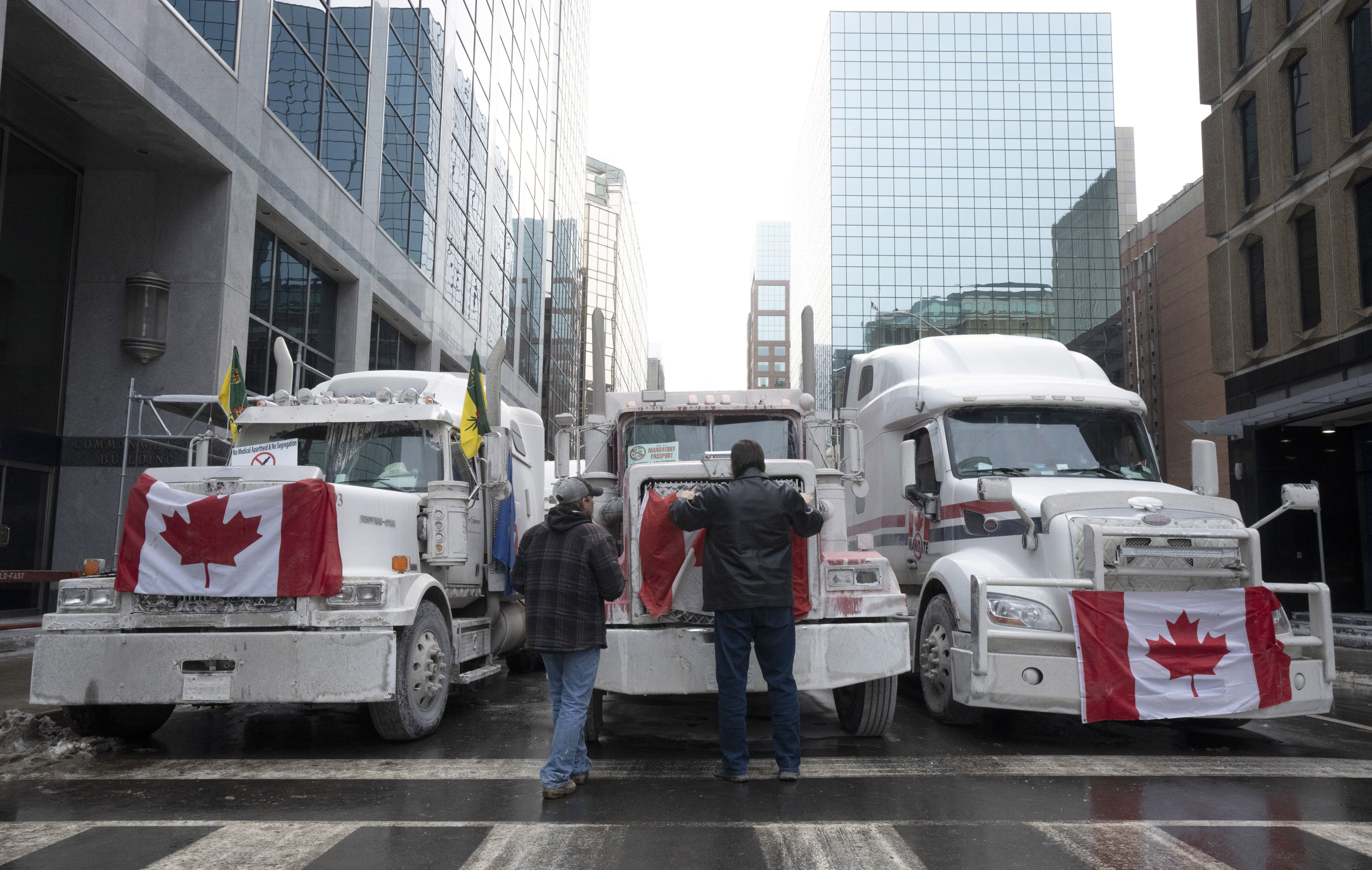 Truck drivers hang a Canadian flag on the front grill of a truck parked in downtown Ottawa, Ontario, near Parliament Hill. Photo: AP