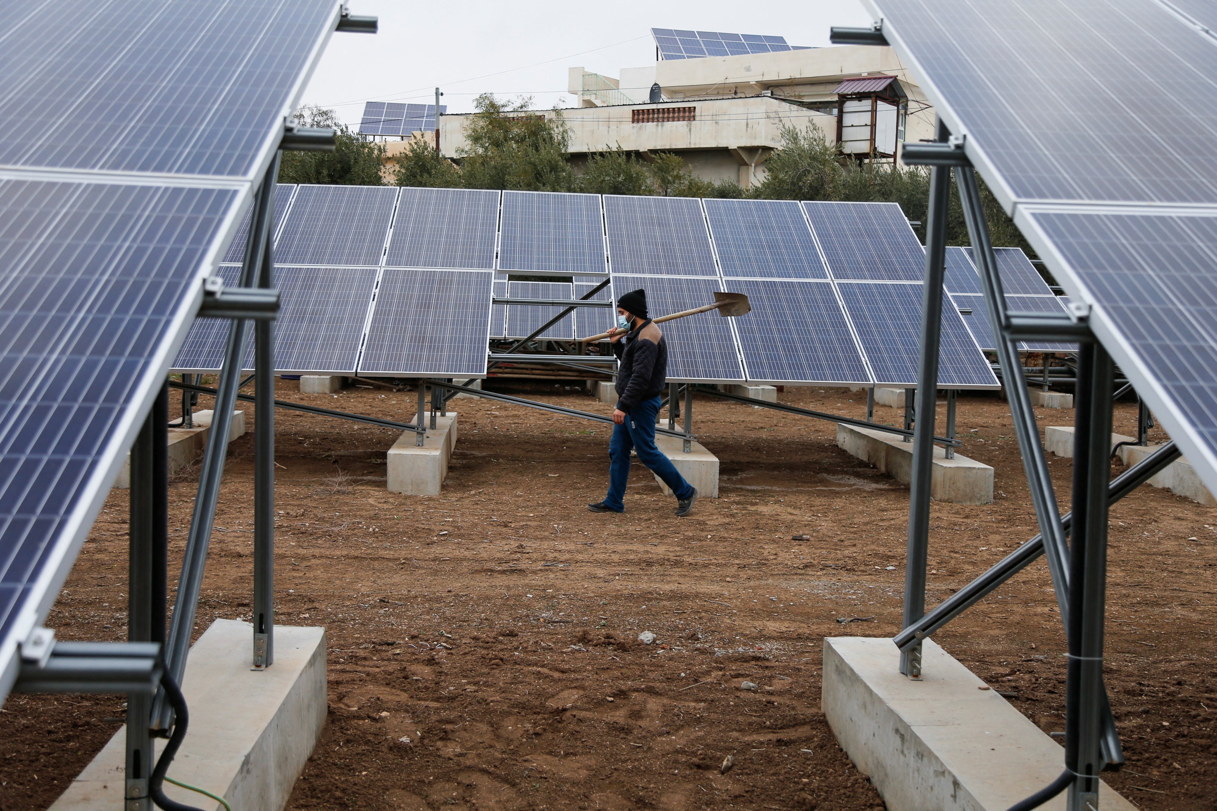 A worker walks near solar panels, which are one of the sustainable energy options that help olive farmers, in Mosul, Iraq on January 26. Asia is in dire need of green finance to fund its sustainable infrastructure projects. Photo: Reuters
