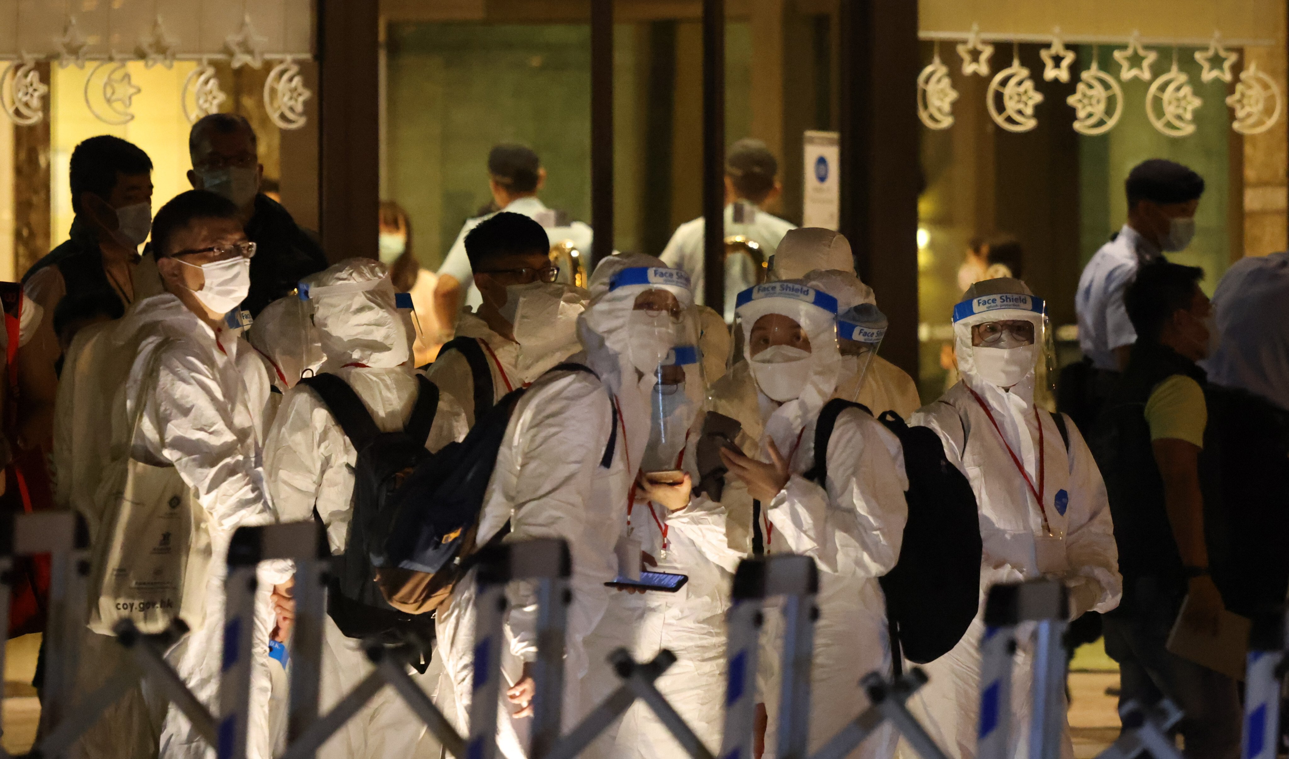 Police and health workers wearing personal protective equipment are seen at a residential tower in Hong Kong under coronavirus lockdown last summer. Photo: K. Y. Cheng