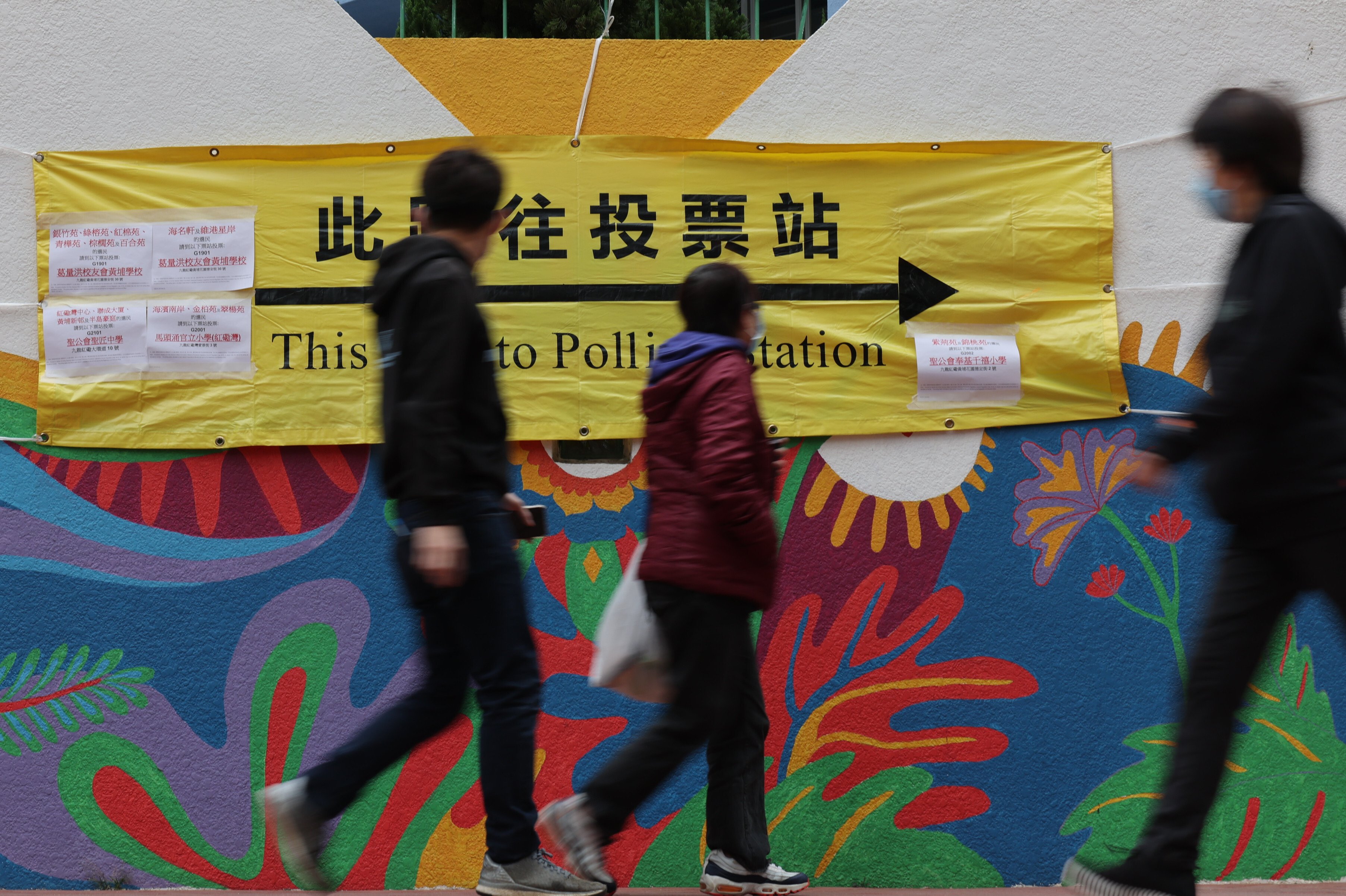 People walk past a banner showing the way to a polling station on December 19 last year, during Hong Kong’s Legislative Council election. Photo: Felix Wong