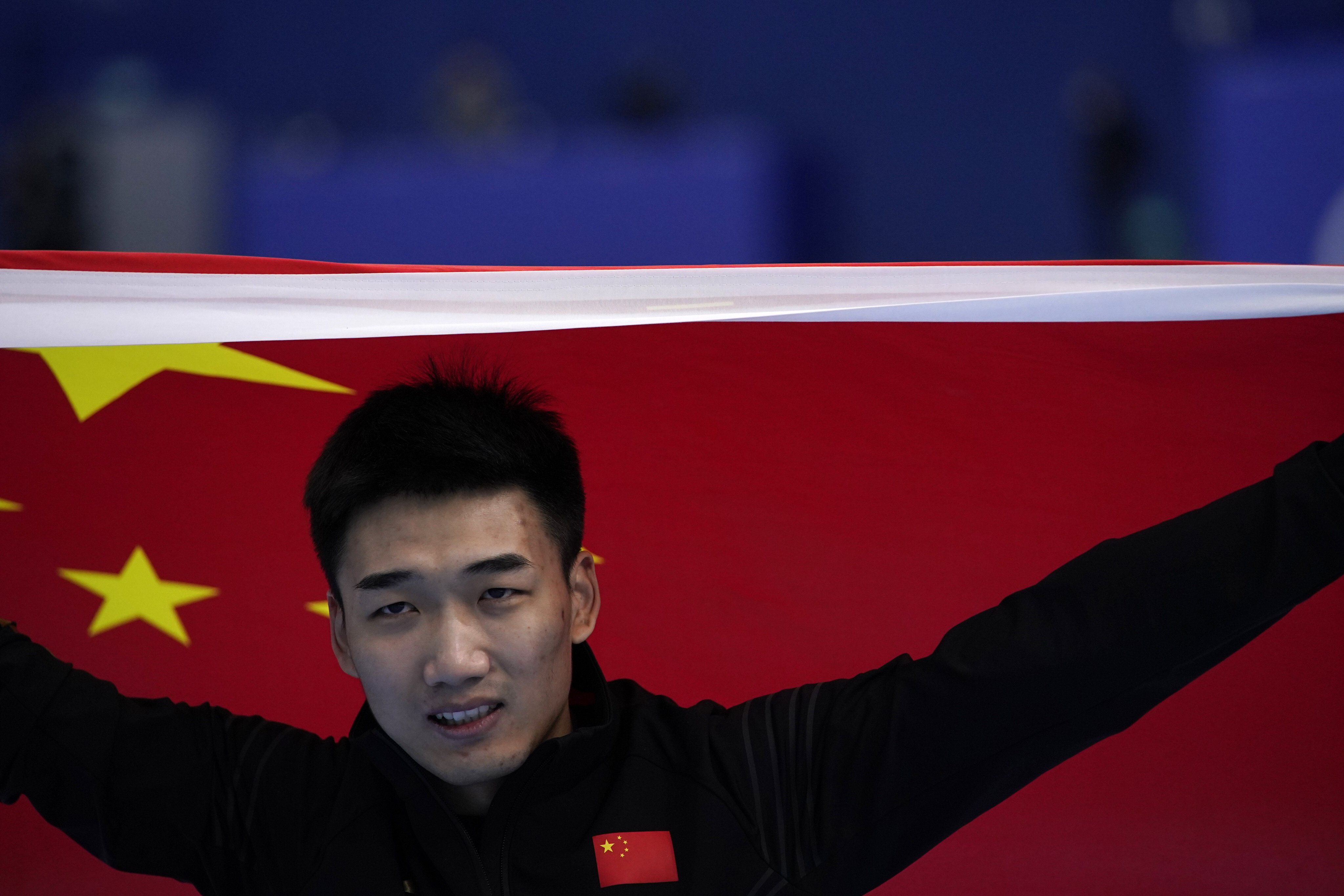 China’s Gao Tingyu carries his country’s flag after winning gold in the men’s speedskating 500m race at the 2022 Winter Olympics. Photo: AP