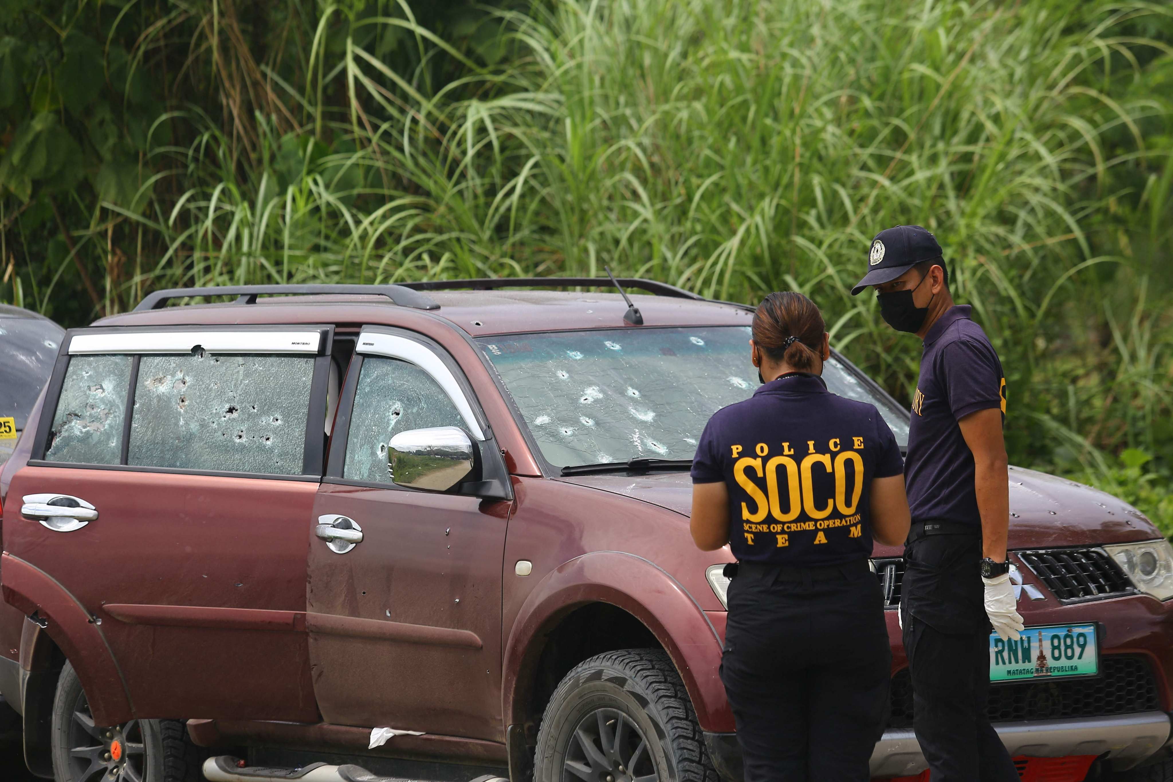 Philippine police look for evidence next to bullet-riddled vehicles. Photo: AFP