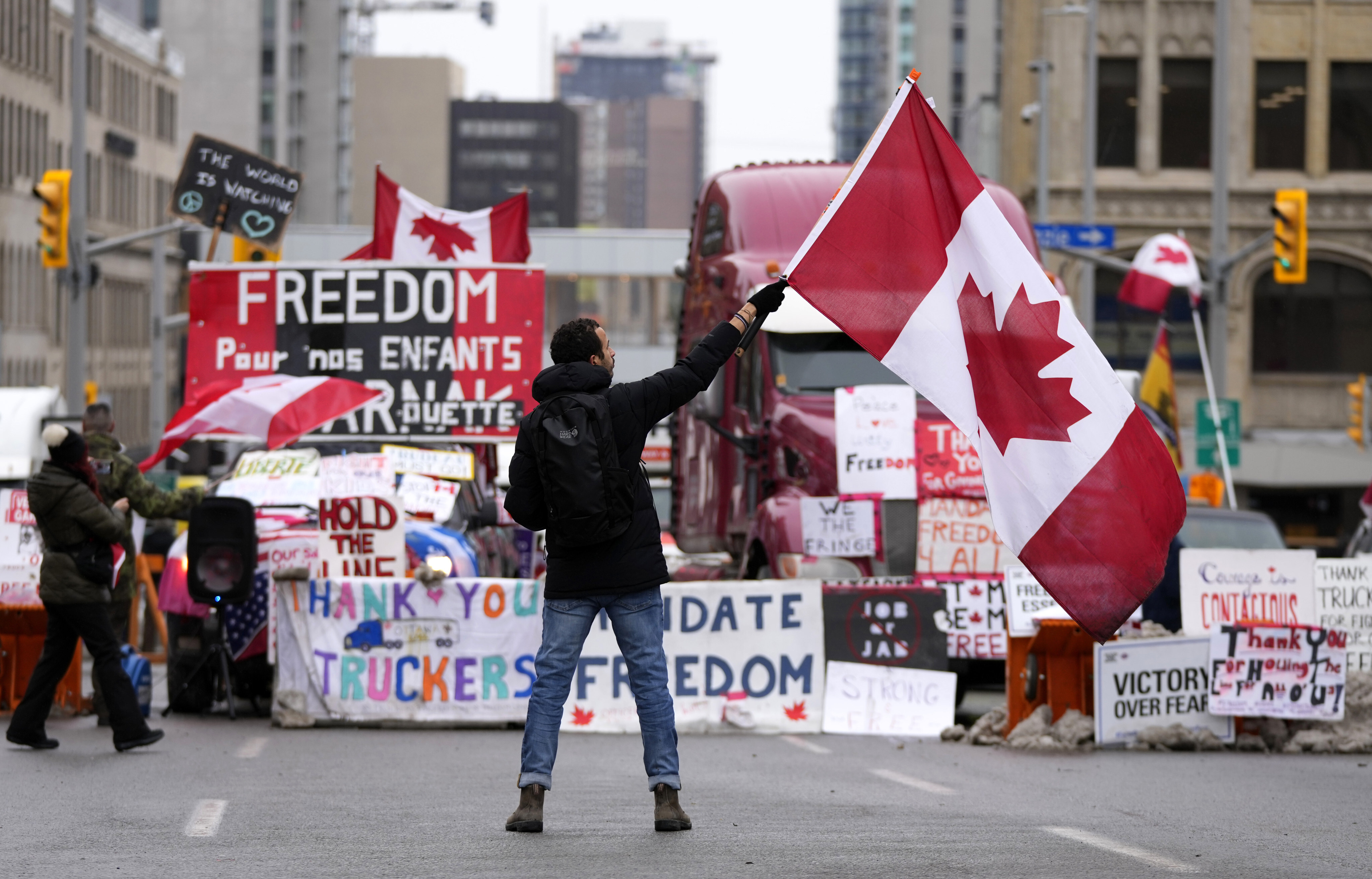 A protester waves a Canadian flag in front of parked vehicles in Ottawa on Friday. Photo: The Canadian Press via AP