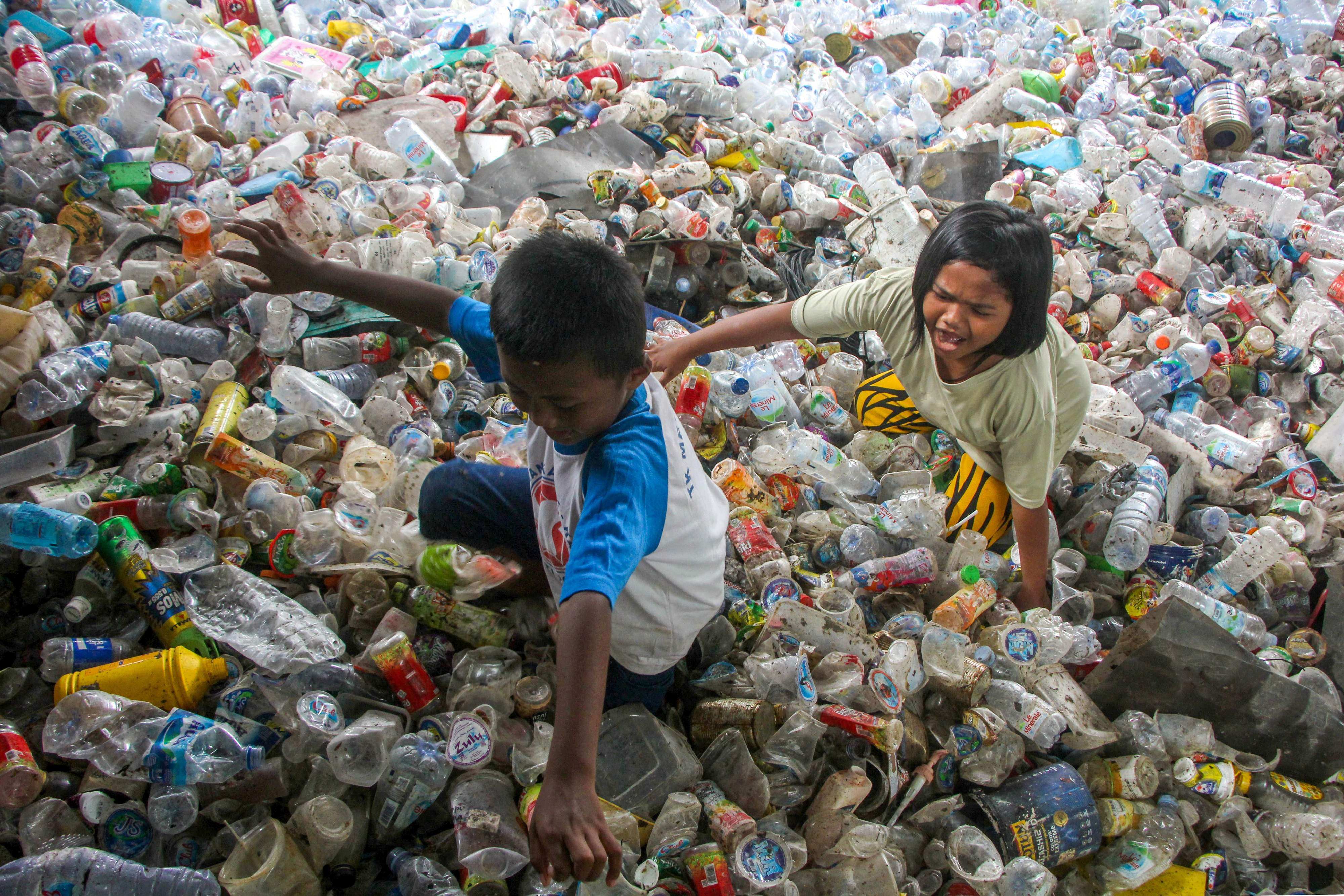 Children play in plastic waste collected for recycling in Makassar, Indonesia. The torrent of man-made chemical and plastic waste worldwide has massively exceeded limits safe for humanity or the planet. Photo: AFP