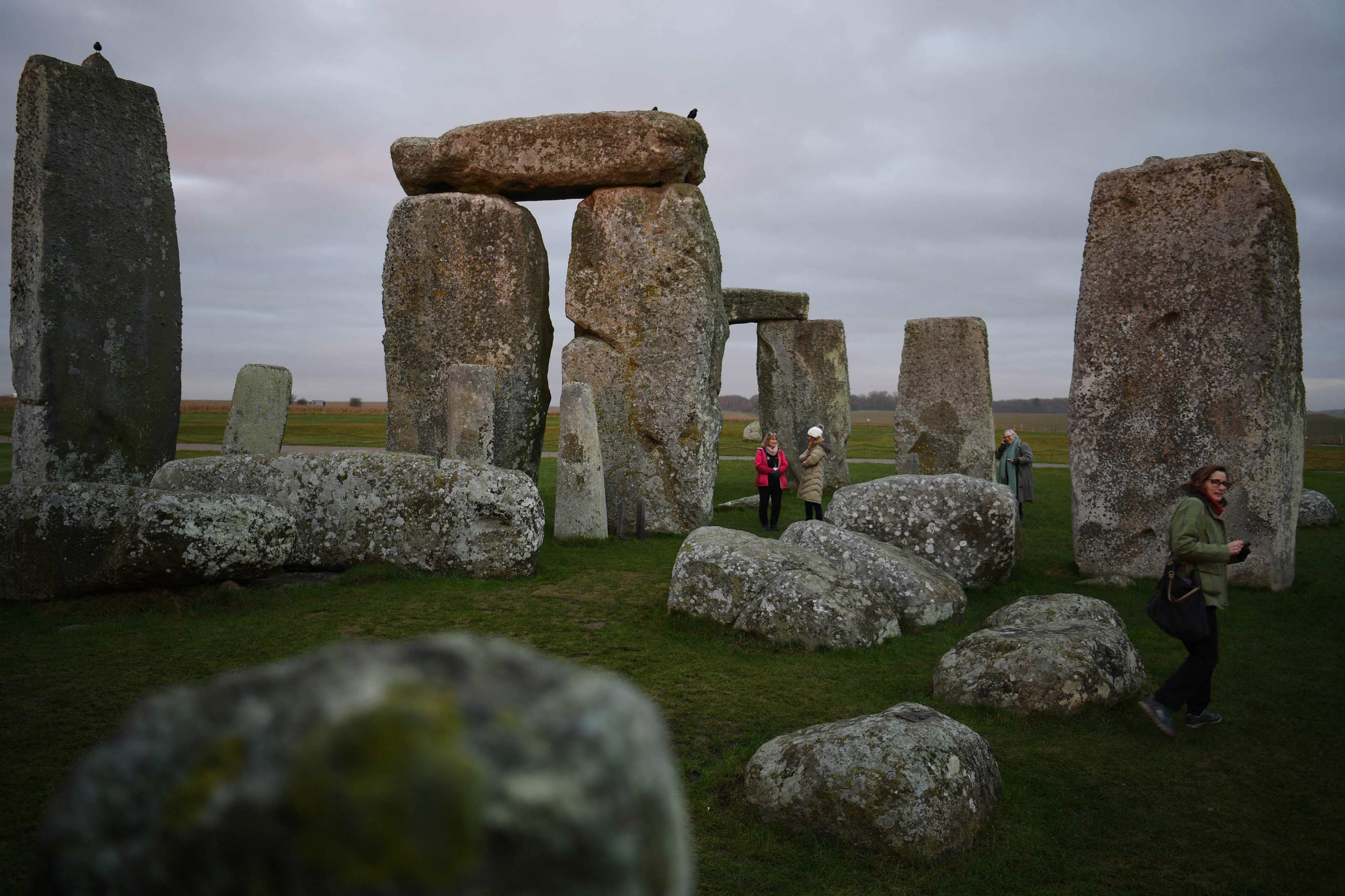 People visit the prehistoric monument Stonehenge near Amesbury in southern England on January 19, 2022. - As the sun rose over the frost on Salisbury Plain, Sarah Greaney summoned the prehistoric ghosts of the hundreds of workers who built Stonehenge. “These people are farmers, they have crops, they have animals and the turning of the year would have been a major part of their lifestyles,” Greaney, senior properties historian at English Heritage, told AFP. It is 4,500 years since labourers from across Britain and the European mainland descended on the vast plain in southwest England, hoisting the huge stones to form the now world-famous landmark. (Photo by Daniel LEAL / AFP) / TO GO WITH AFP STORY BY Anna CUENCA