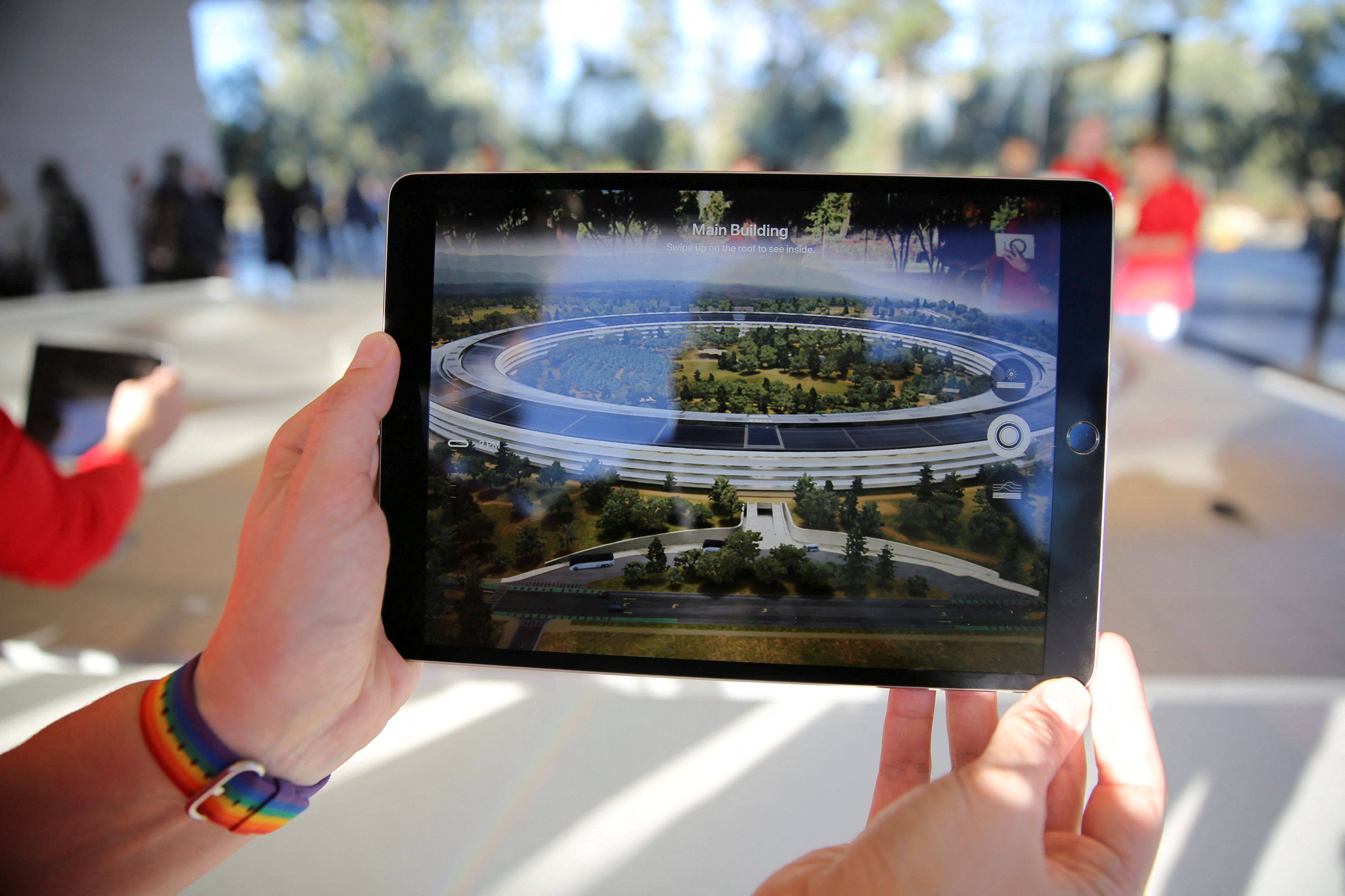 An Apple employee uses an iPad with an augmented reality app on it to show off features of the new Apple Park at the Apple Visitor Center in Cupertino, California on November 17, 2017. Photo: Reuters