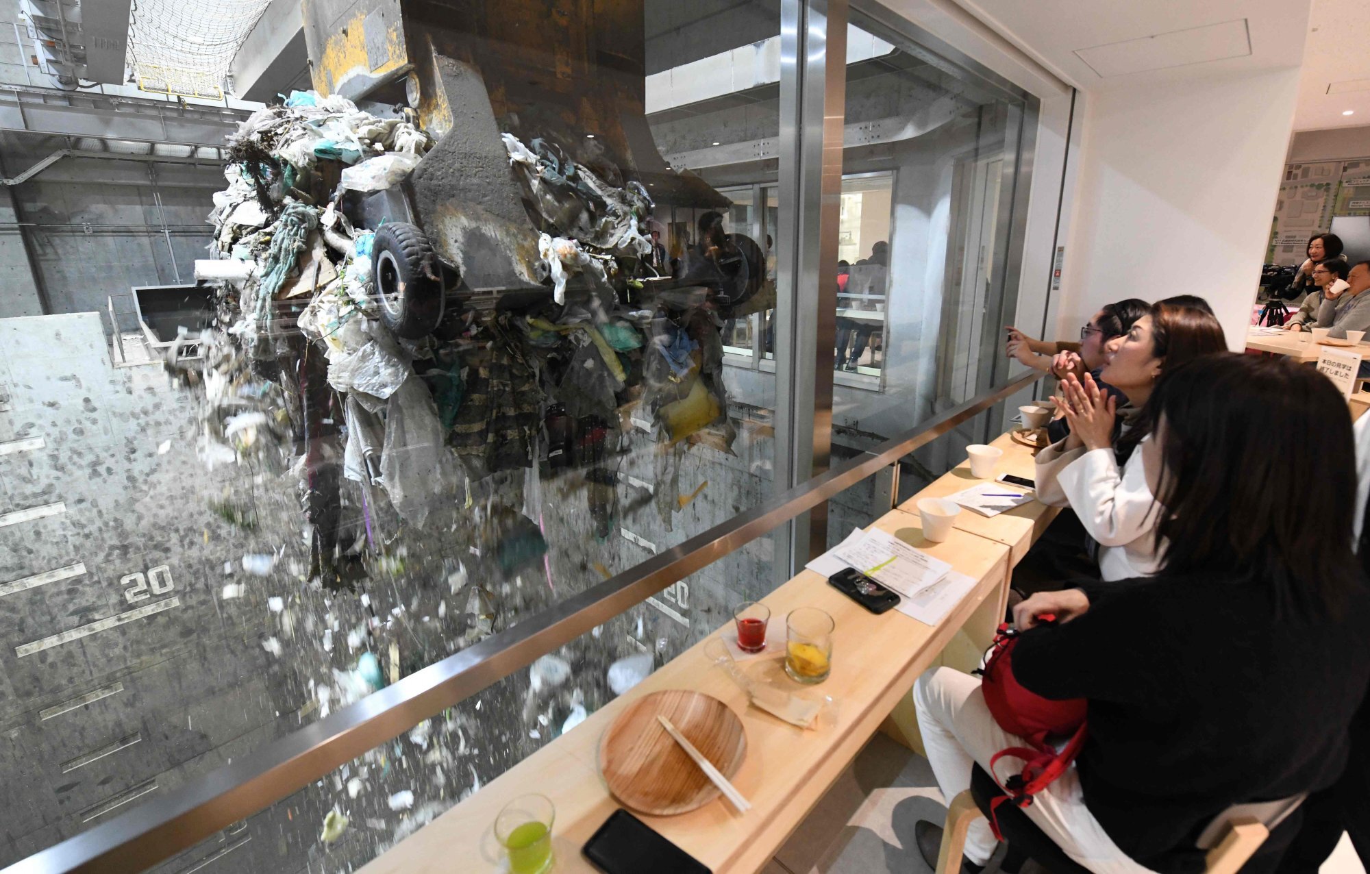 Customers watch a crane pick up rubbish for incineration at a combustible waste pit while having a drink and snack at the “Gomi Pit” bar in Tokyo. Photo: AFP