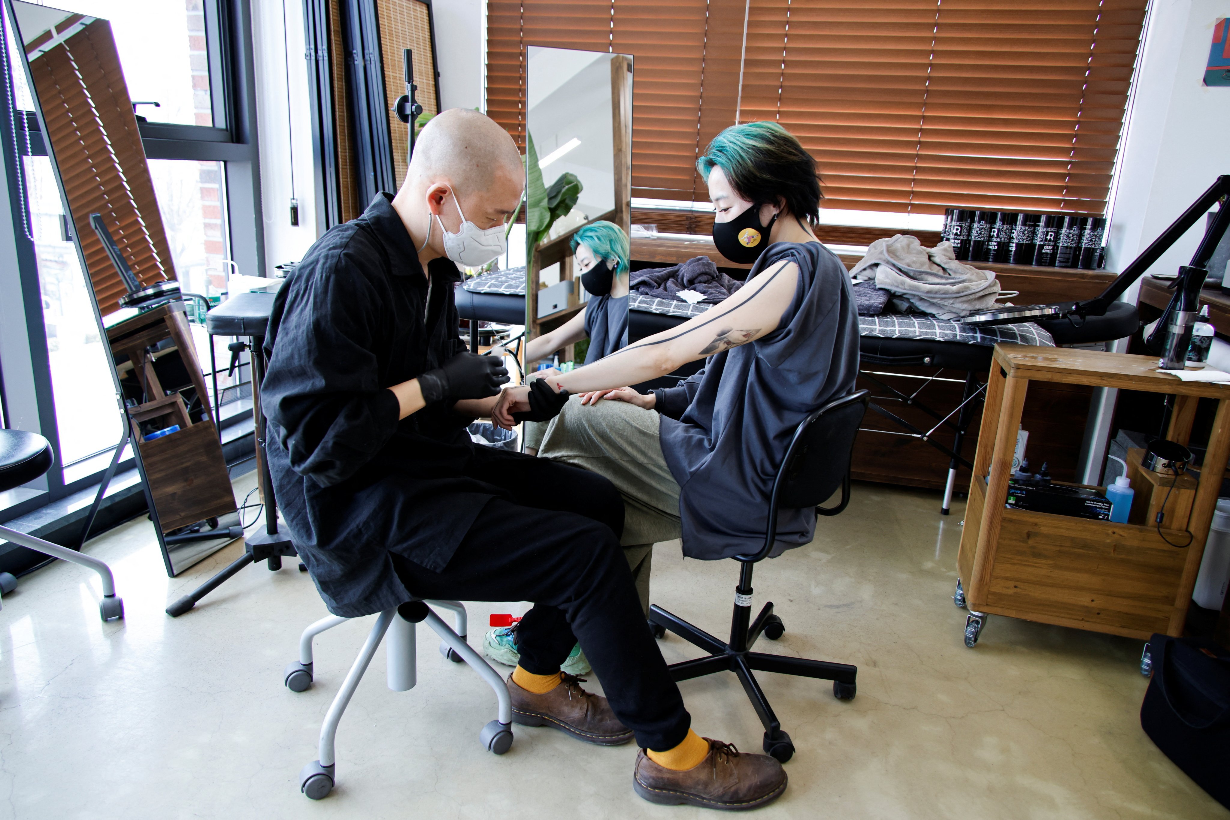 Tattooist Kim Do-yoon attends to a customer in his studio in Seoul. Photo: Reuters