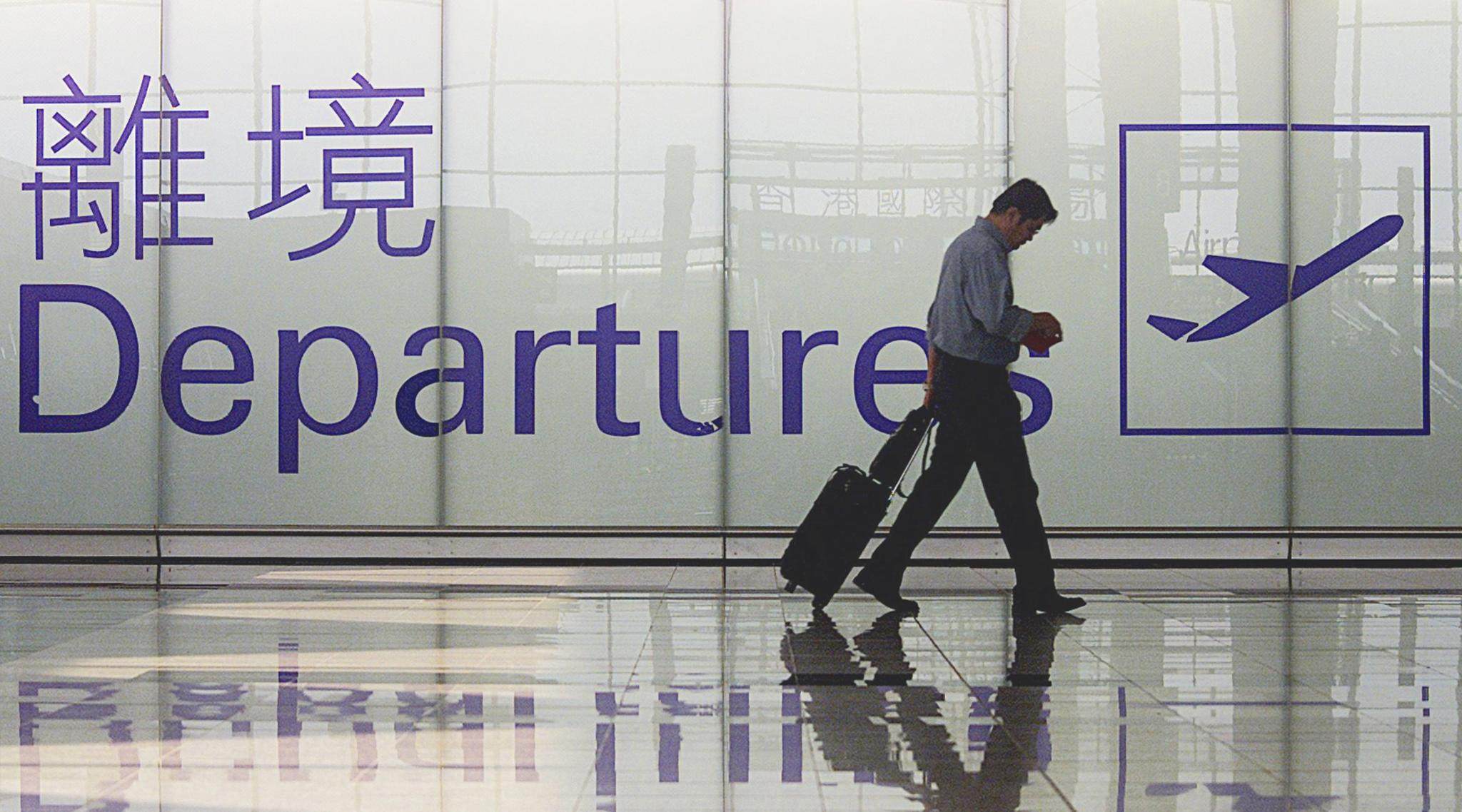 A passenger walks towards the departure hall at Hong Kong’s Chek Lap Kok airport 05 March 2002 in Hong Kong.  Hong Kong Financial Secretary Antony Leung said in his budget speech 06 March 2002 tourism was an area which would drive growth in Hong Kong  AFP PHOTO/Mike CLARKE (Photo by MIKE CLARKE / AFP)