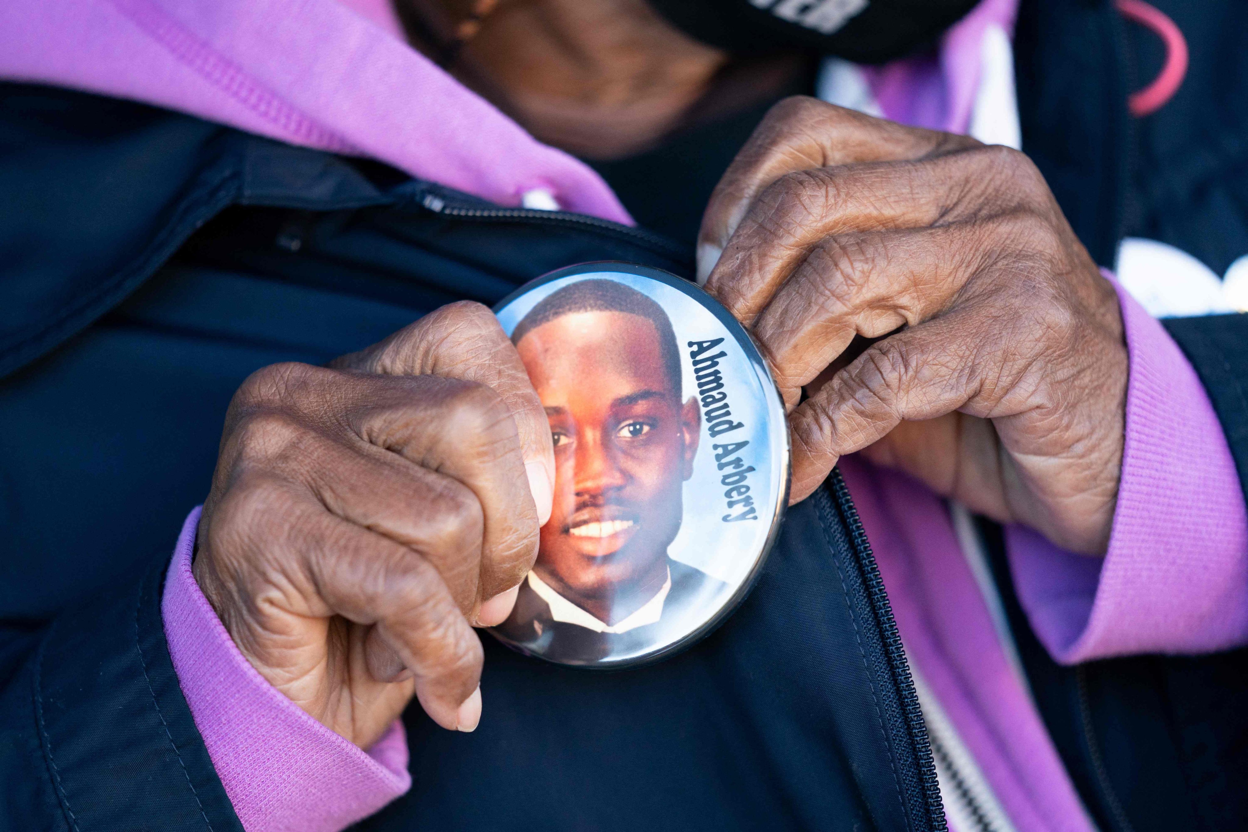 A woman puts on a button for Ahmaud Arbery outside the Glynn County Courthouse in Georgia in November. Photo: AFP
