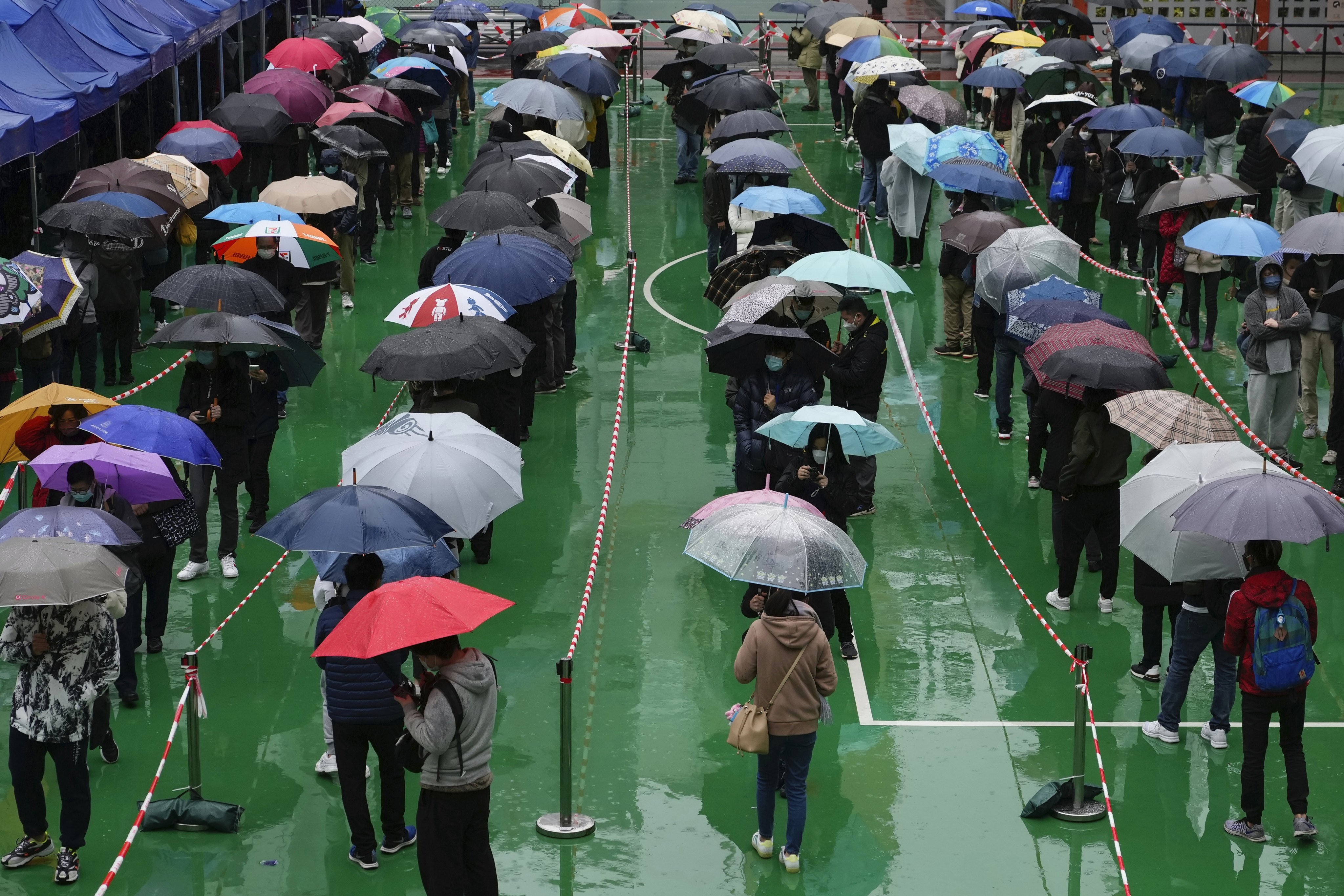 Residents queue in the rain for Covid-19 testing at a temporary centre on February 21. Hong Kong will carry out citywide testing in March as it introduces new tougher social distancing measures. Photo: AP