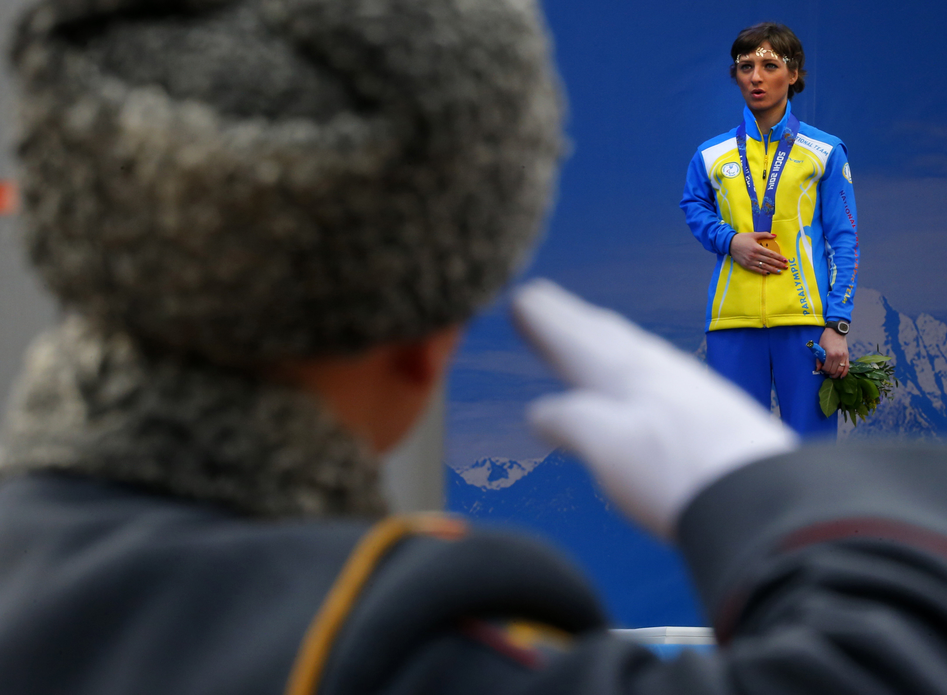 FILE - A Russian honour guard soldier salutes as Ukraine’s Oleksandra Kononova covers her gold medal with her hand after winning the women’s biathlon 12.5km standing event during a medal ceremony at the 2014 Winter Paralympics. Photo: AP
