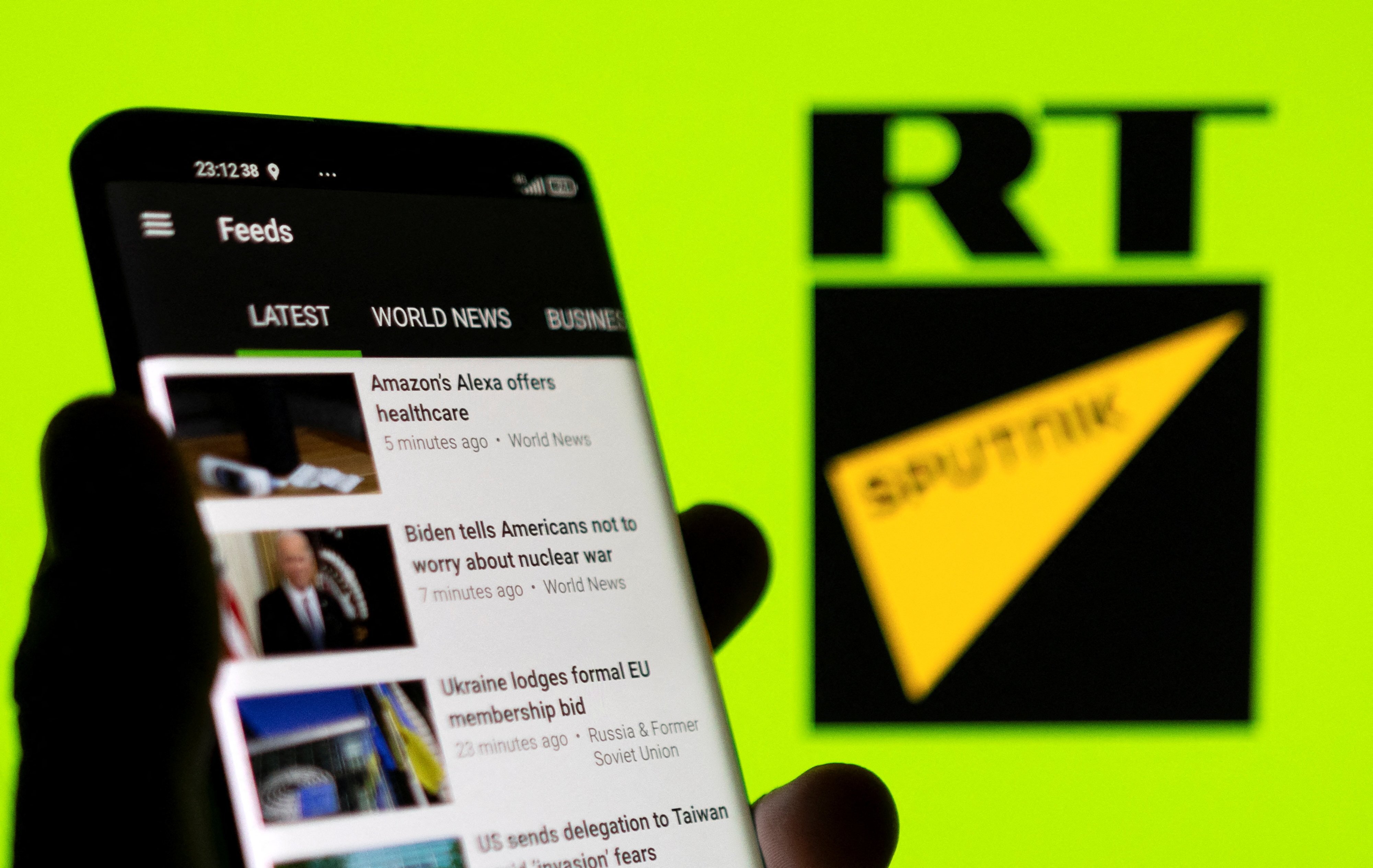 The RT app seen on a smartphone in front of the RT and Sputnik logos in this illustration taken February 28, 2022. Photo: Reuters