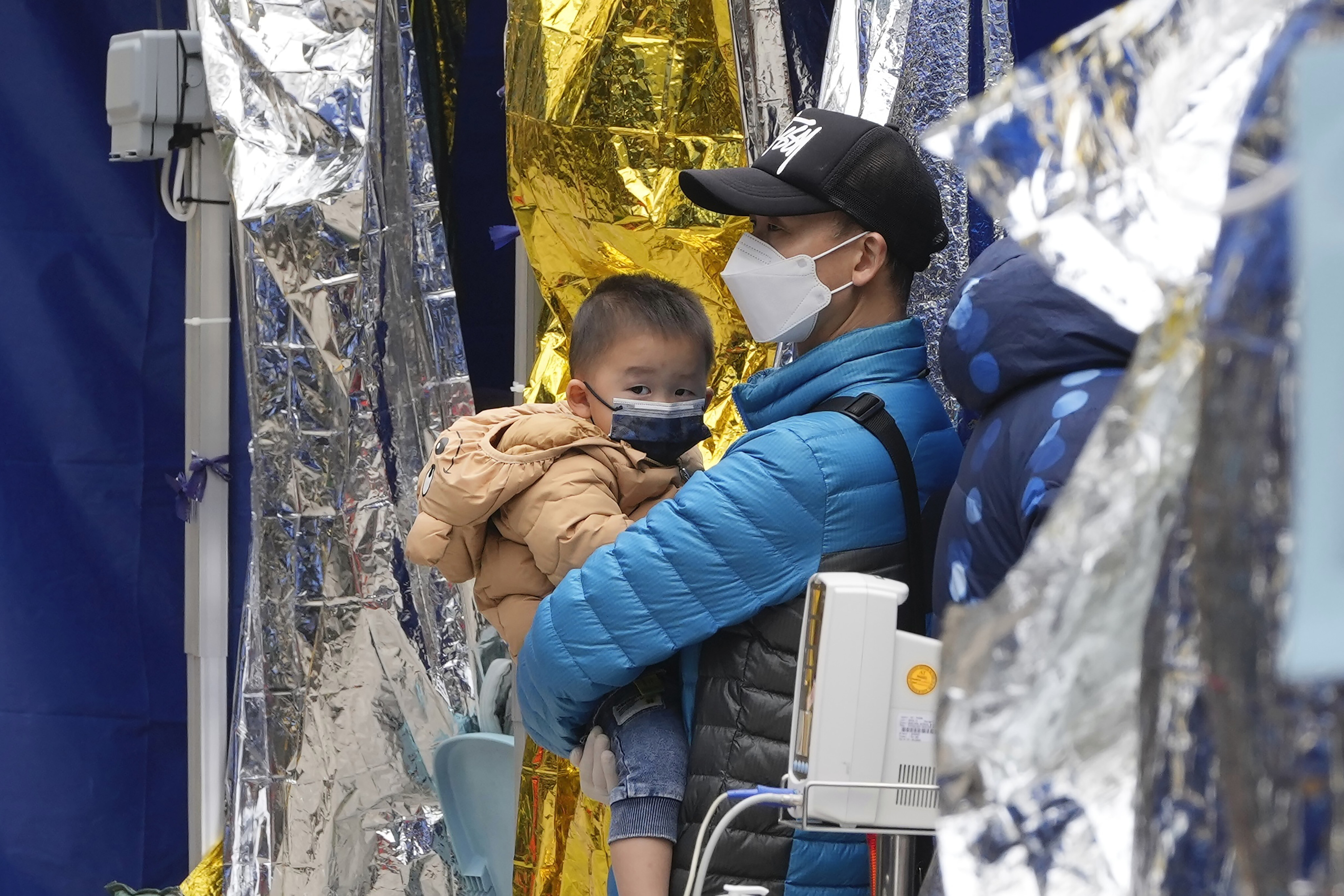 A man and child wait at a temporary treatment area outside a hospital on February 18. Since the start of the pandemic, Hong Kong has maintained a policy of isolating and hospitalising all positive cases, regardless of age, leading to fears of family separation. Photo: AP
