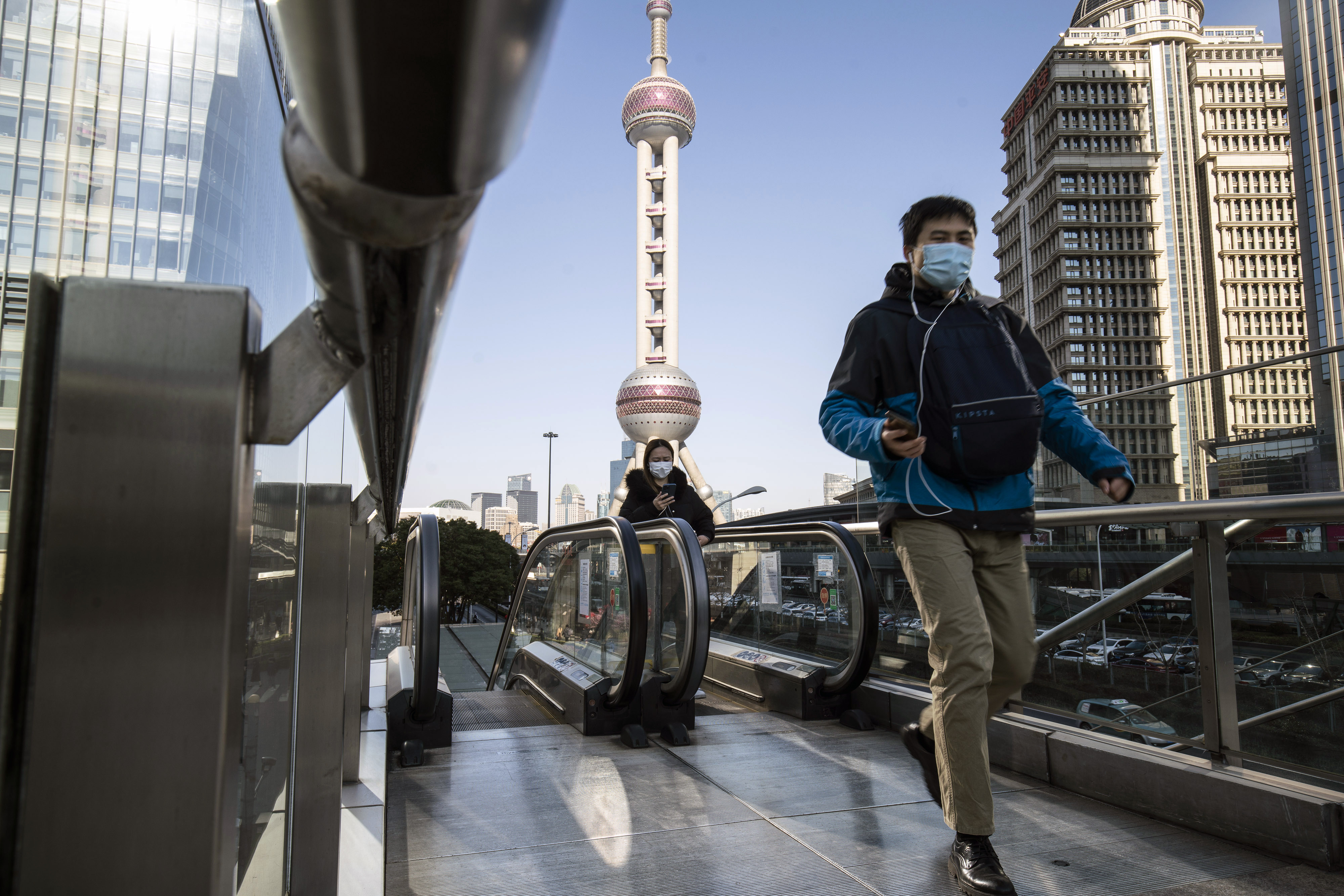 Pedestrians wearing protective masks ride on an escalator in Pudong’s Lujiazui Financial District in Shanghai in February 2021. Photo: Bloomberg