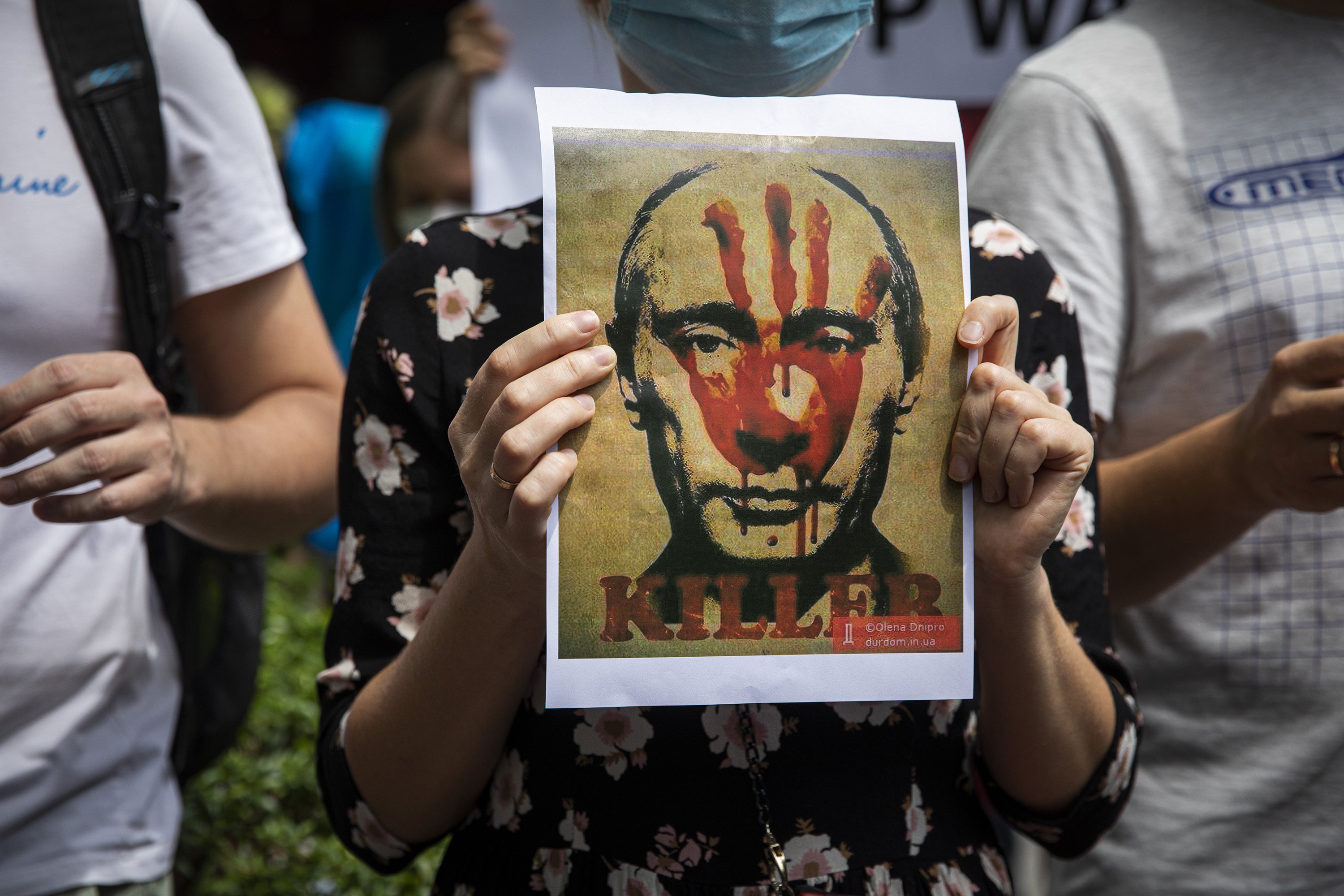 A Ukrainian protester holds up a poster of Russian President Vladimir Putin with the word “killer” during a rally outside the Russian embassy in Bangkok, Thailand in February. Photo: TNS