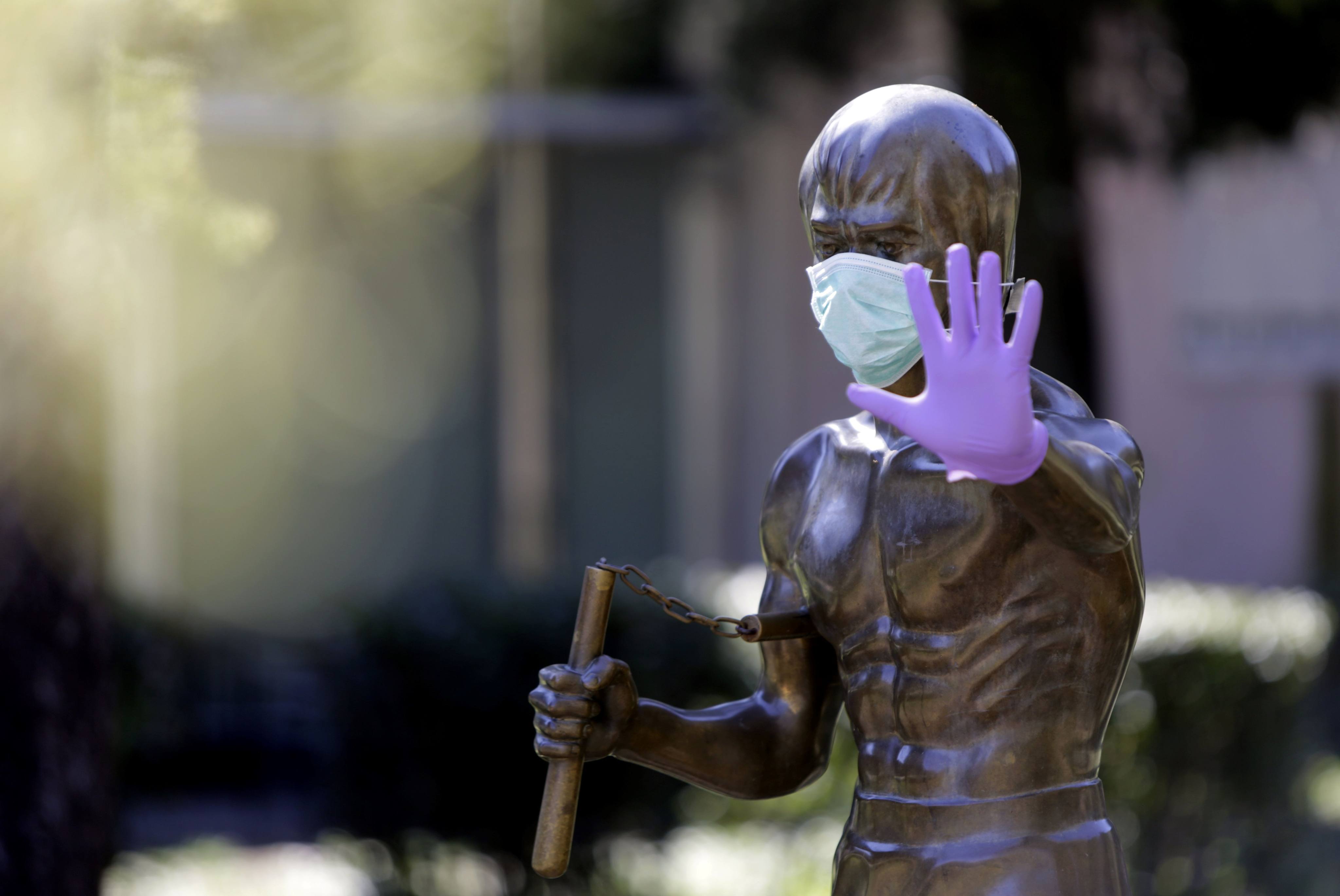 A statue dedicated to actor Bruce Lee is covered with surgical gloves and a face mask at a park in Mostar, Bosnia and Herzegovina. File photo: AFP