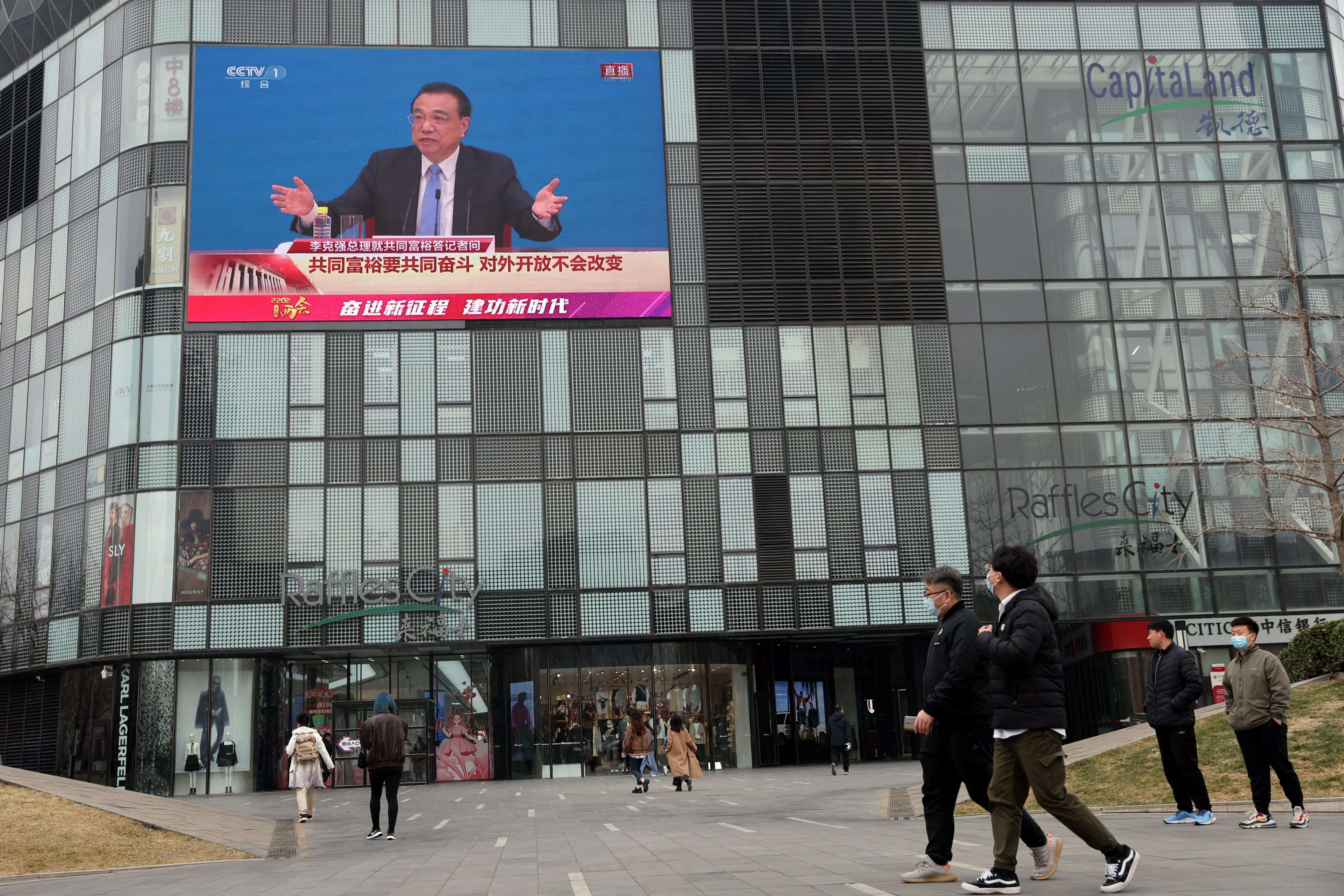 People walk past a screen showing Premier Li Keqiang giving a news conference to close the Two Sessions in Beijing, on March 11. Photo: Reuters