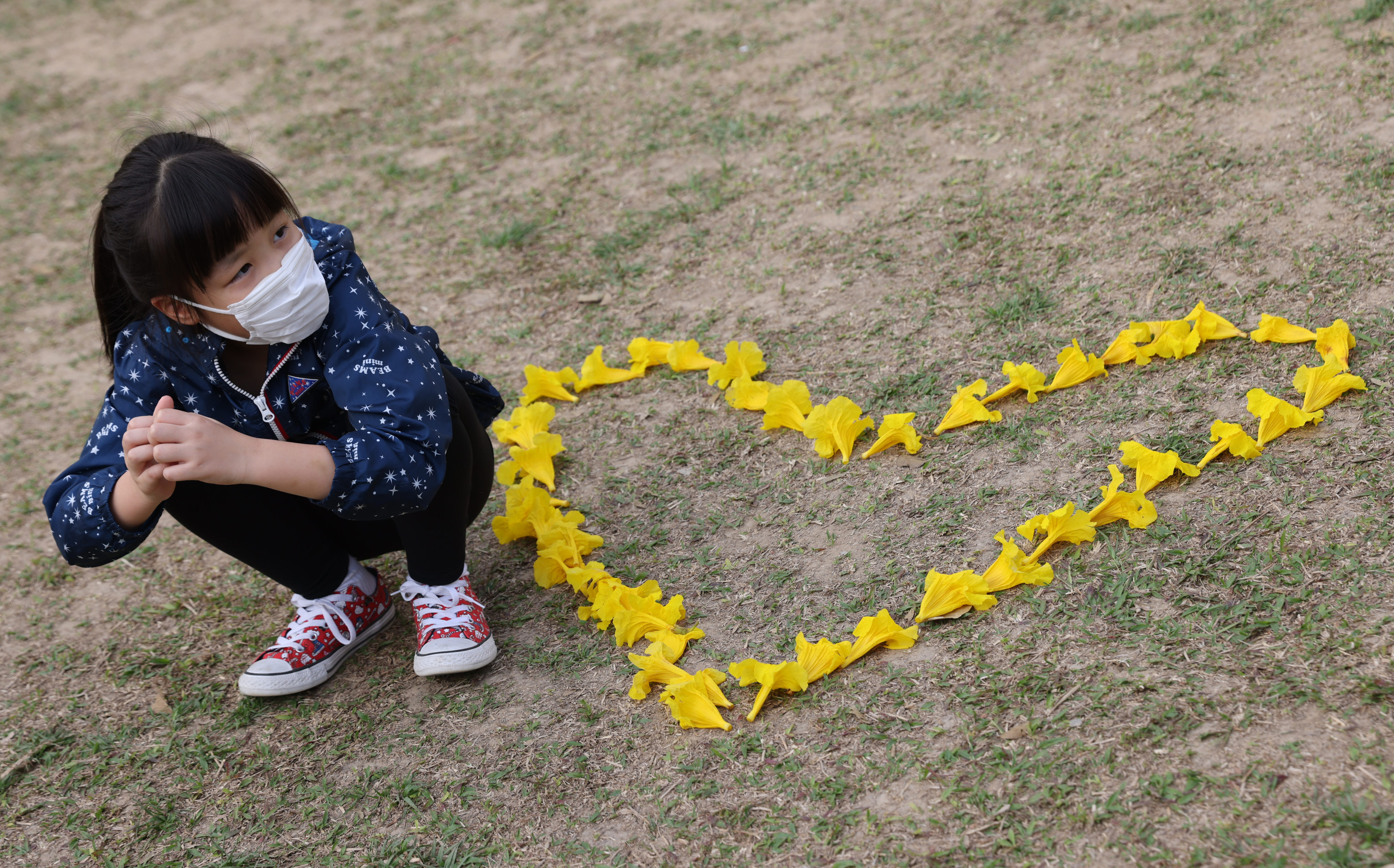 People admire and take pictures of the blossoming yellow Golden Trumpet Tree flowers at Nam Cheong Park in Nam Cheong on March 17. Research suggests people are more likely to engage in healthy behaviours such as wearing masks when they feel empowered to take care of themselves during the pandemic. Photo: Nora Tam
