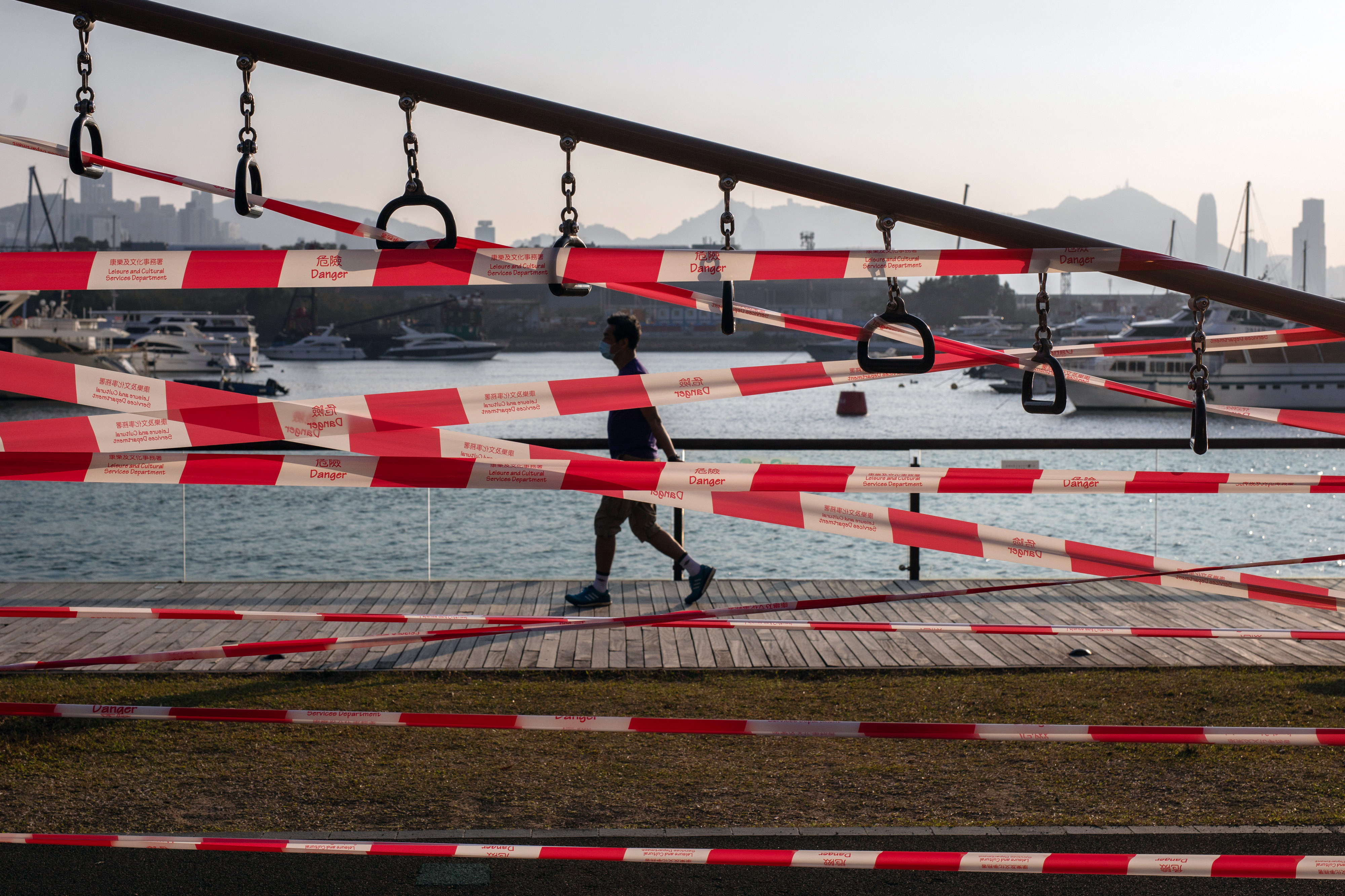 A pedestrian walks past tape cordoning off an outdoor firness area, closed due to Covid-19 restrictions, at the Kwun Tong Promenade in Hong Kong, on March 3. Photo Bloomberg