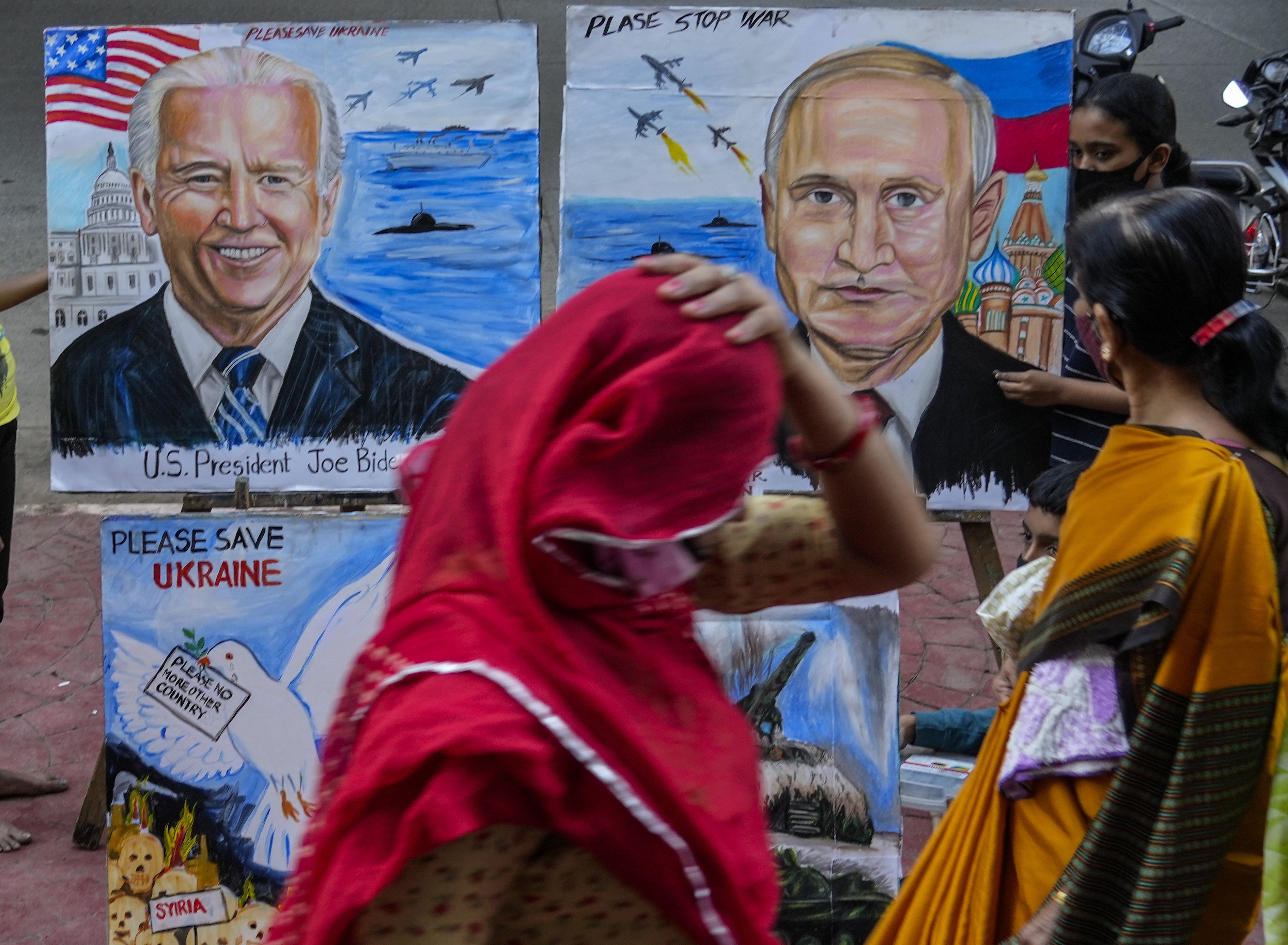 A woman adjusts her sari as she walks past students from an art school displaying their work calling for peace in Ukraine, in Mumbai, India, on February 21. Photo: AP