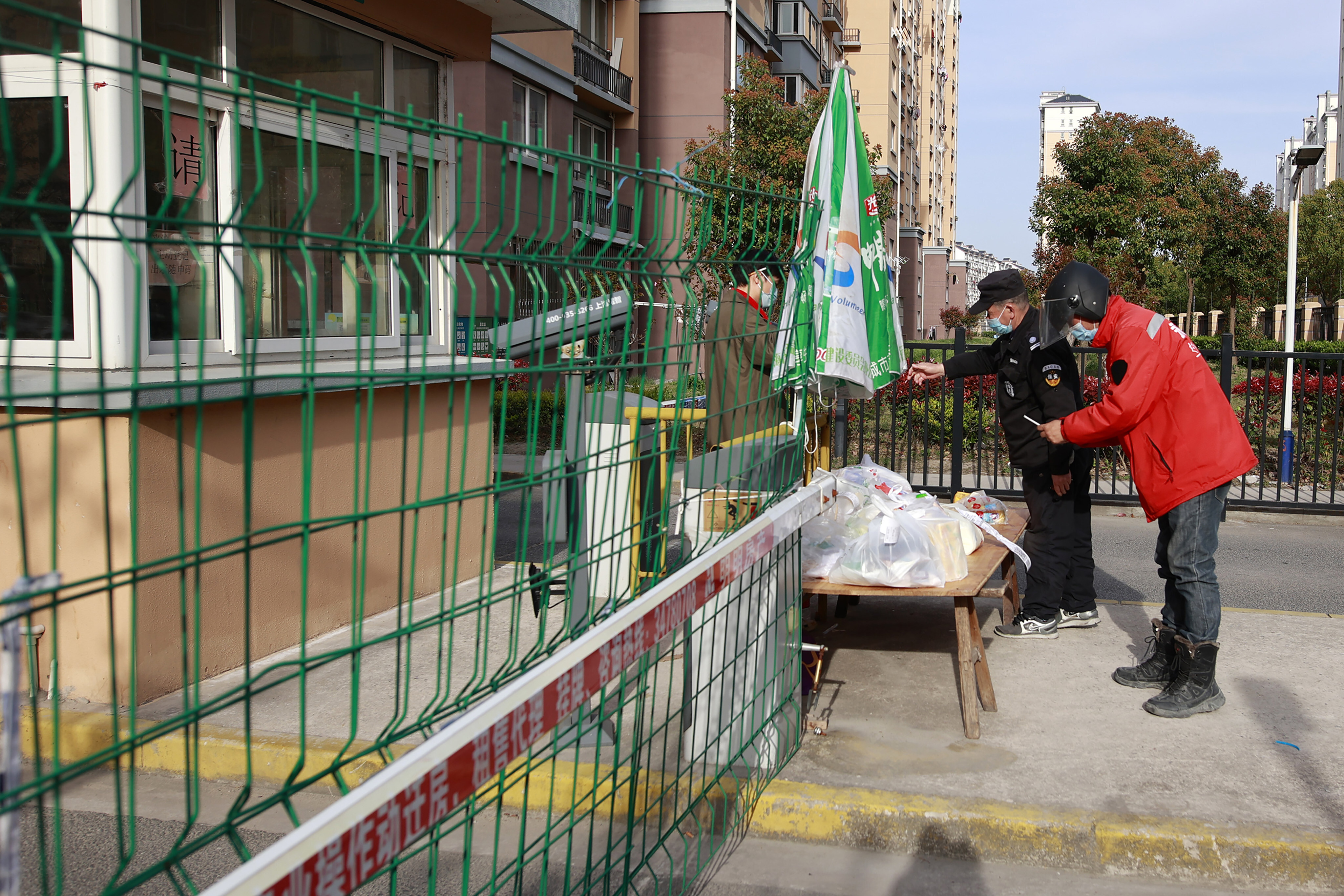 A security guard helps a resident collect their deliveries as more items are placed on a table at the gate of a residential community under lockdown in Shanghai on March 29. A two-phase lockdown of Shanghai’s 26 million people is testing the limits of China’s hardline “zero-Covid” strategy, which is shaking markets far beyond the country’s borders. Photo: AP