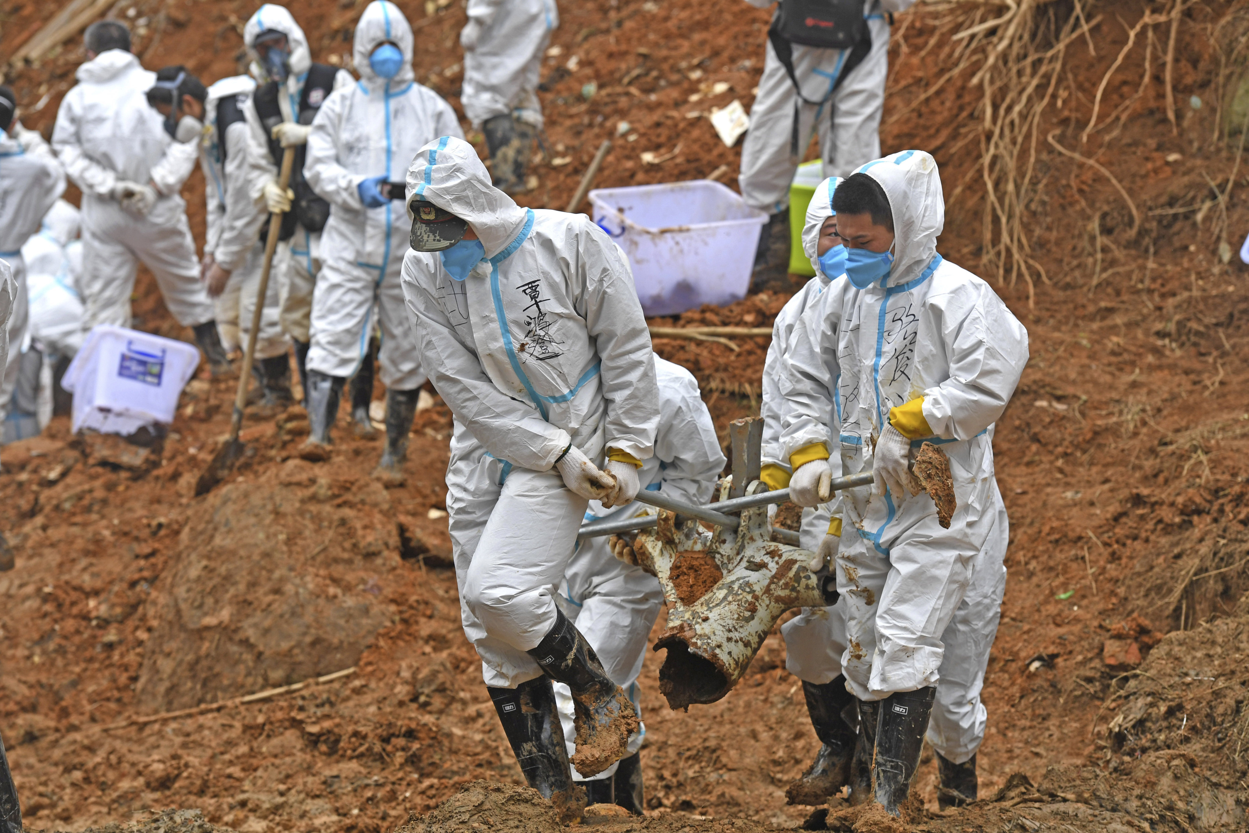 Rescuers carry a piece of plane wreckage from the China Eastern flight crash site on March 25. Photo: Xinhua via AP