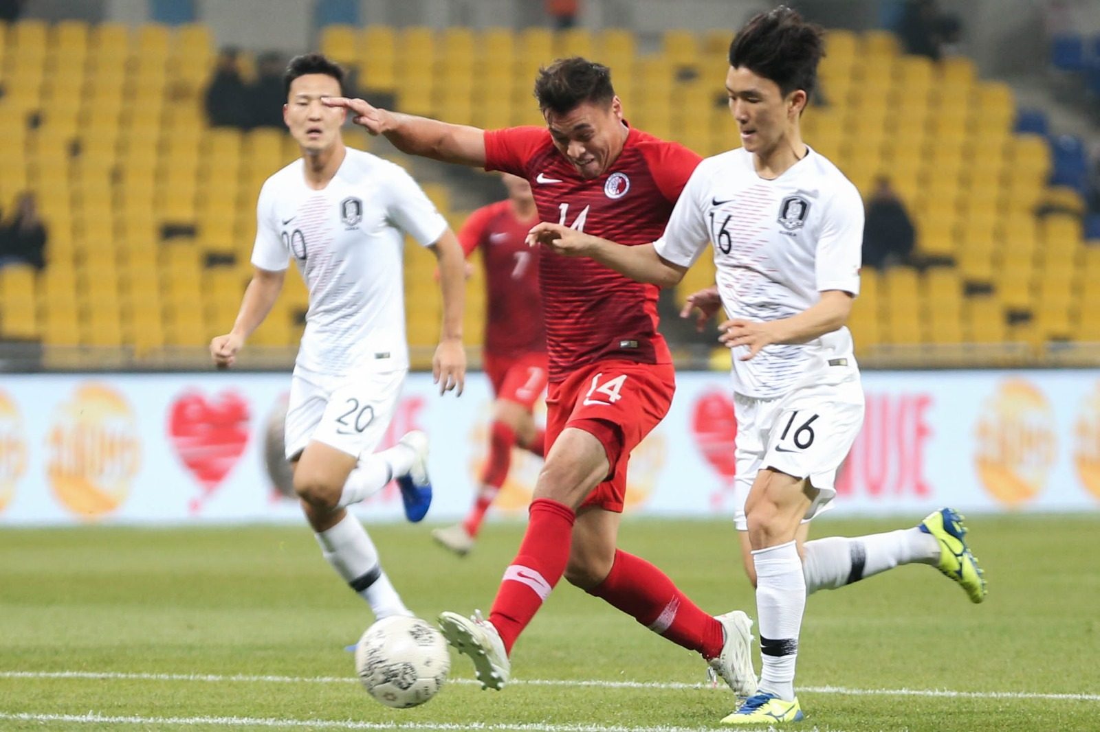 James Ha of Hong Kong (red shirt) tries to outpace his South Korean markers during their match at the 2019 EAFF Championship in Busan. Photo: HKFA